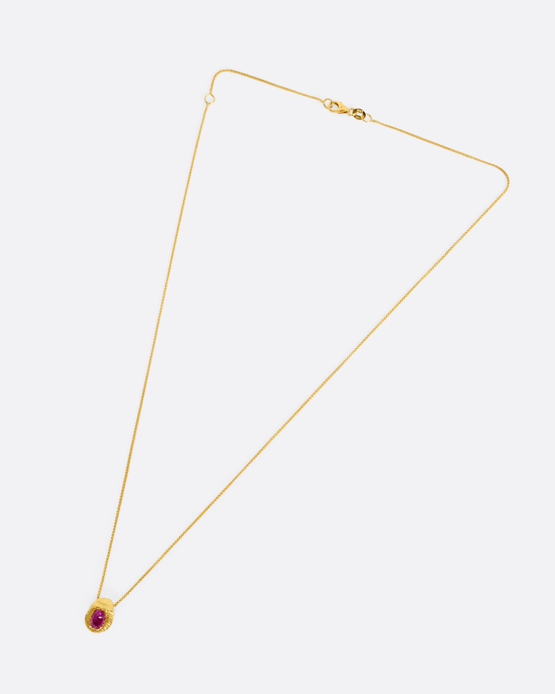 A yellow gold necklace with a ruby pendant shown from the front.