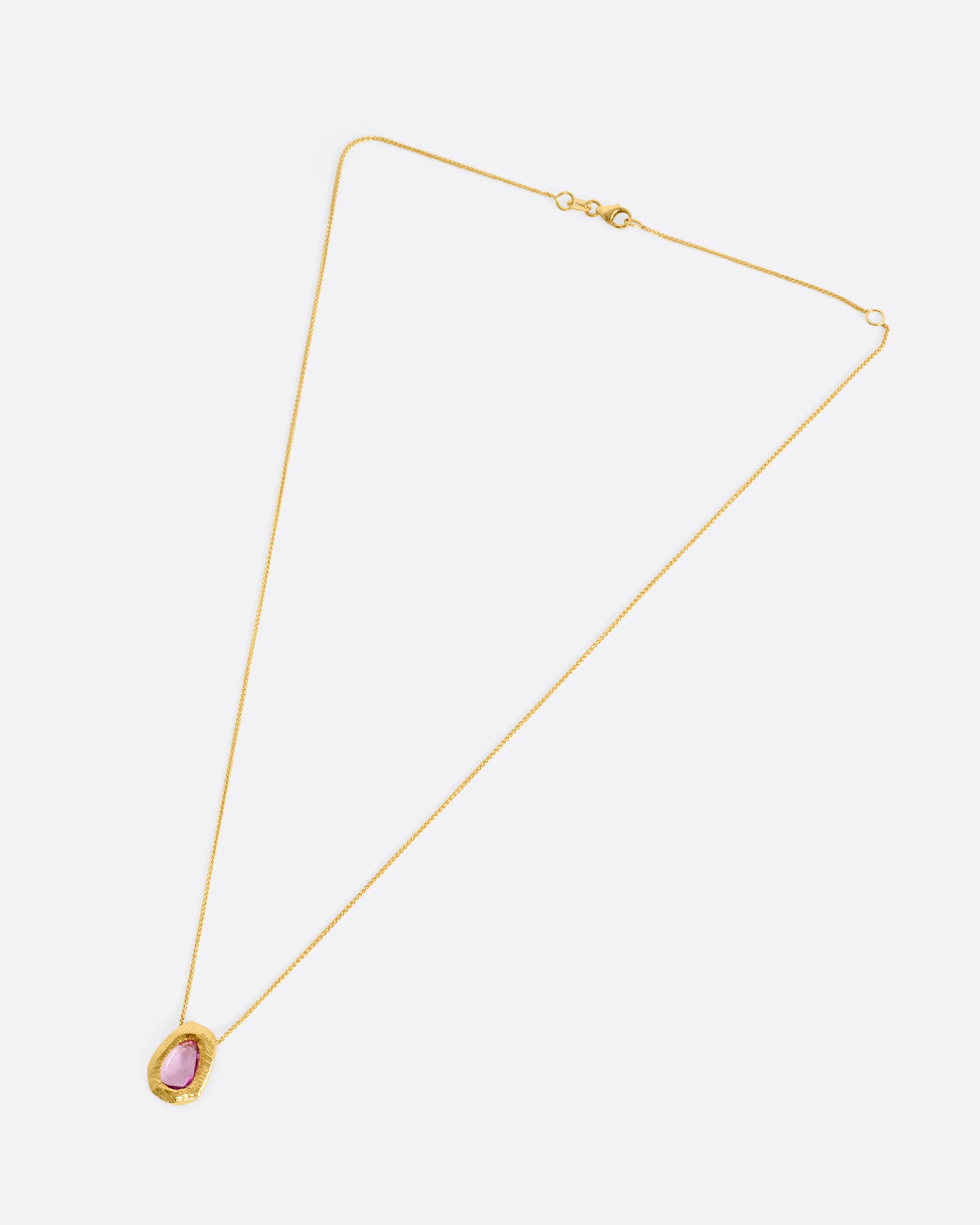 A yellow gold necklace with a pink sapphire pendant, shown from the front.