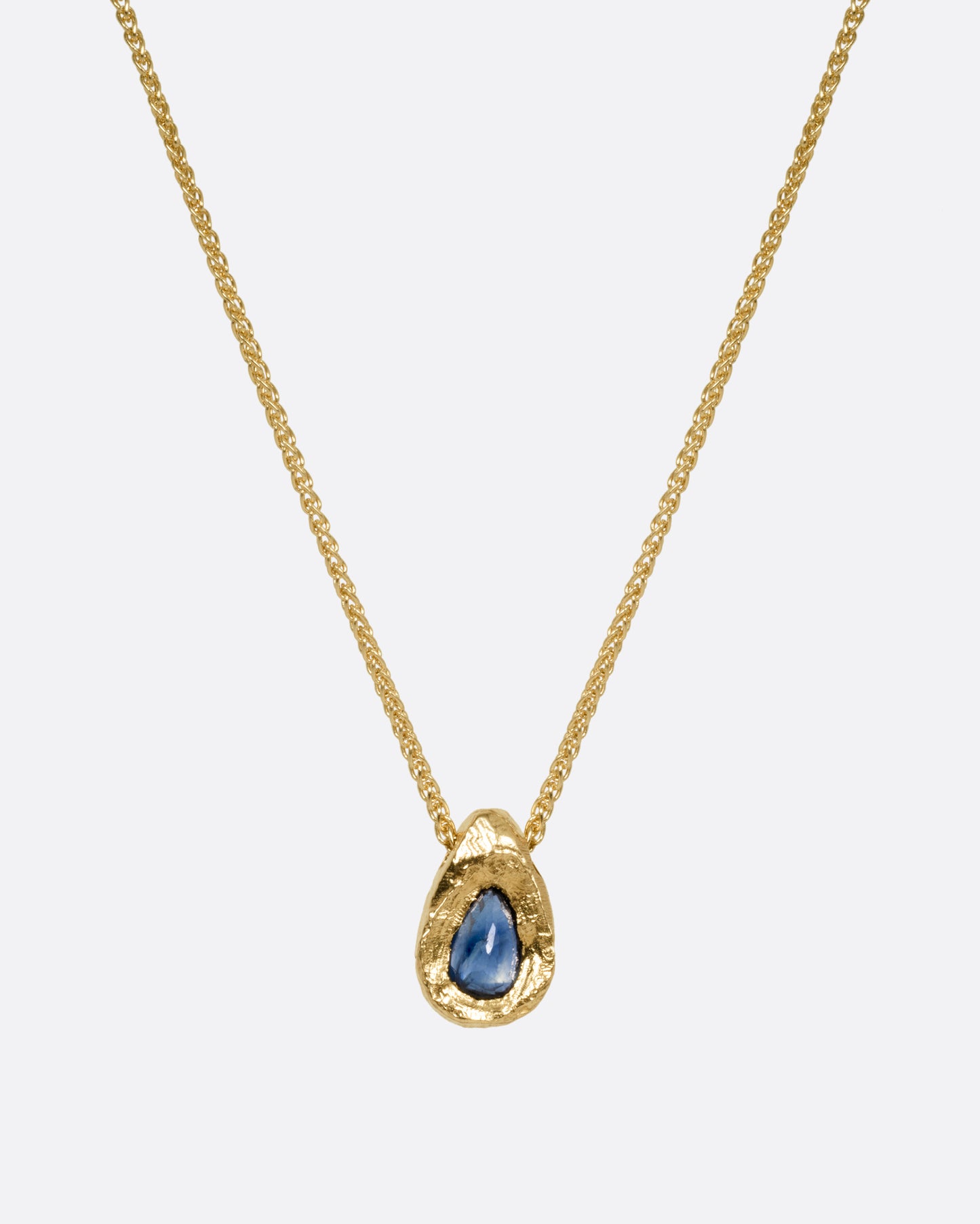 A yellow gold necklace with a blue sapphire pendant shown from the front.