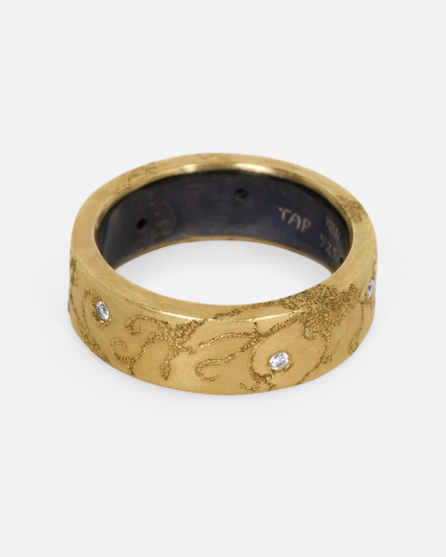 A yellow gold ring with etched oceanic images and diamond accents throughout, shown from the front.
