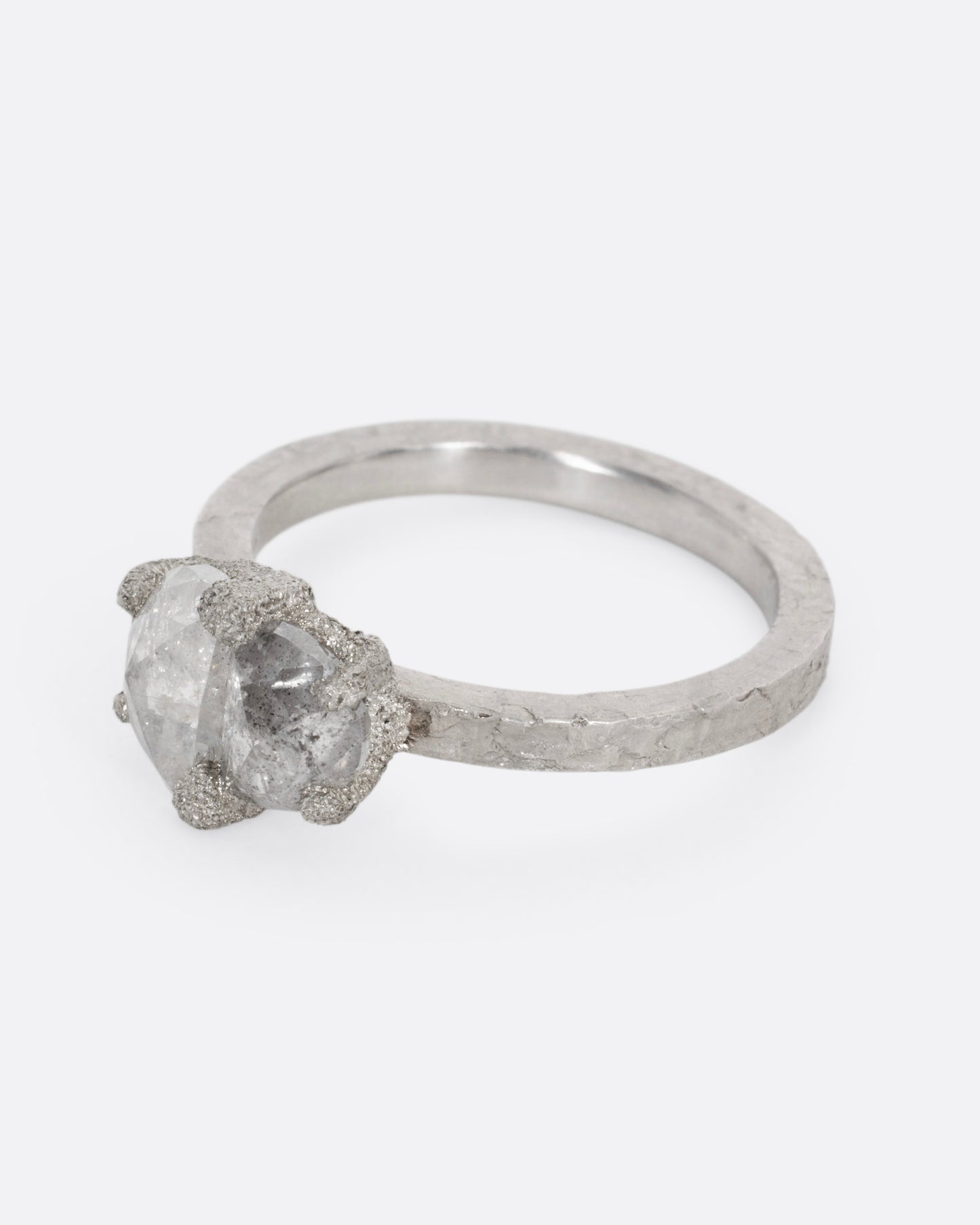 A platinum ring with two prong set rose cut diamonds, shown from the side.