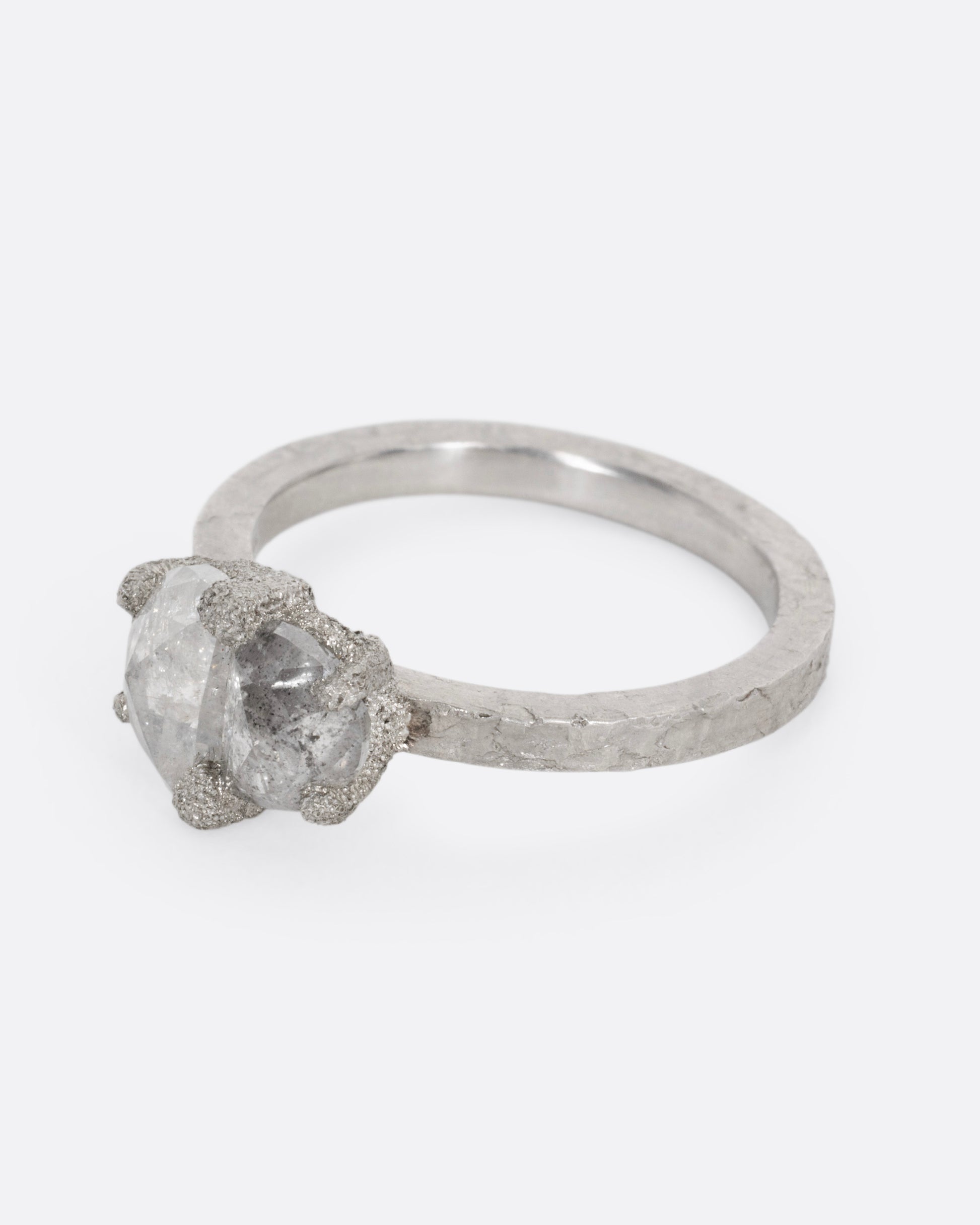 A platinum ring with two prong set rose cut diamonds, shown from the side.