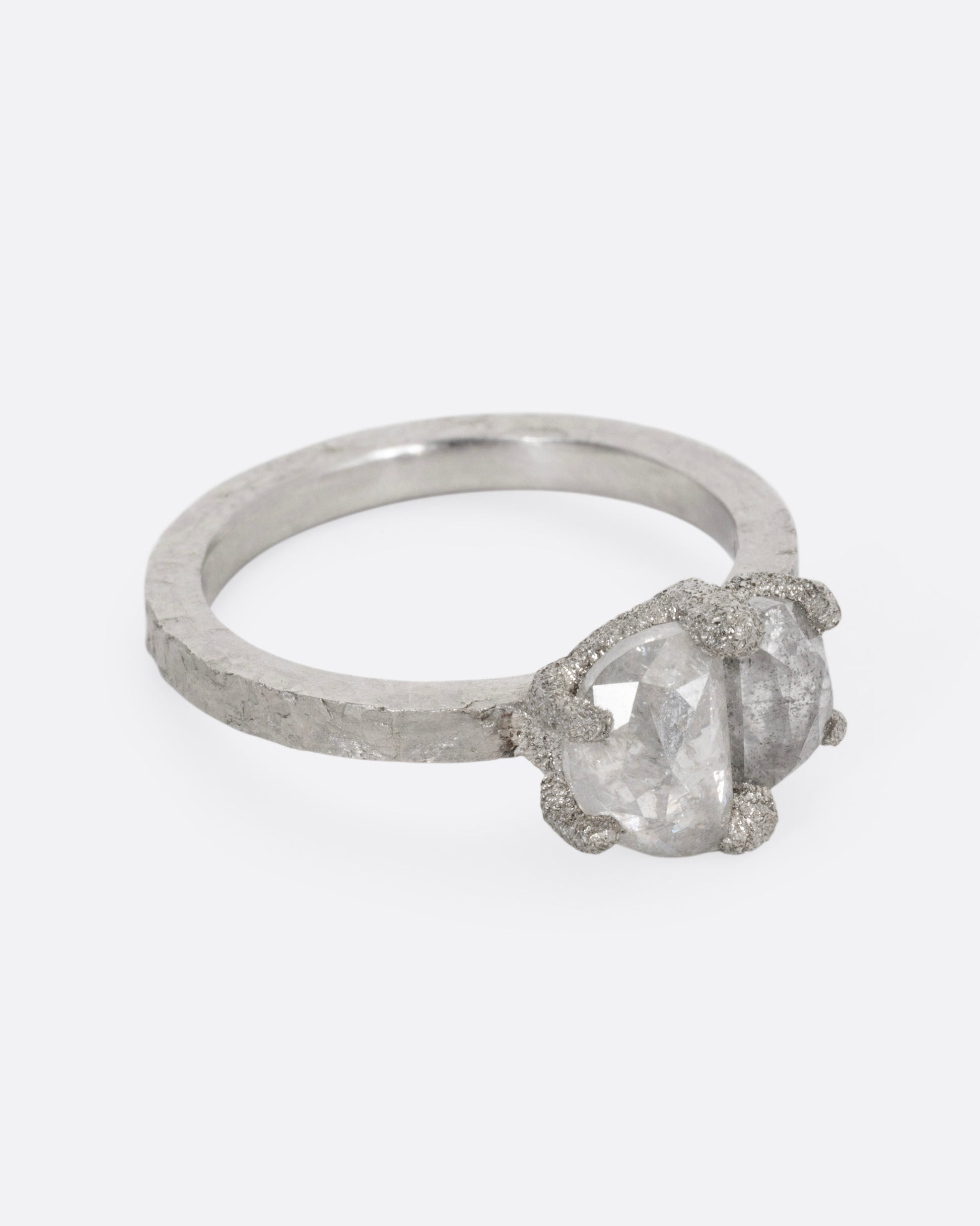 A platinum ring with two prong set rose cut diamonds, shown from the side.