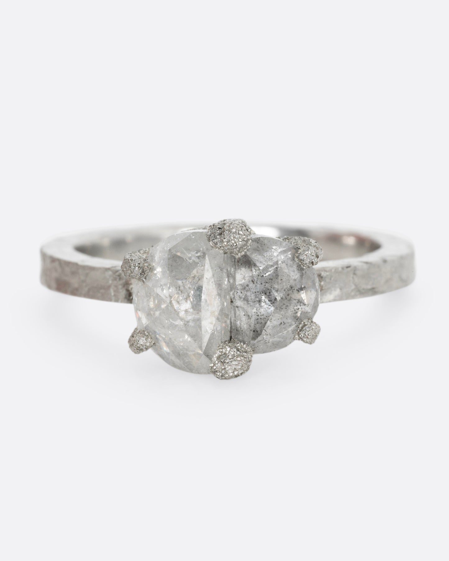 A platinum ring with two prong set rose cut diamonds, shown from the front.