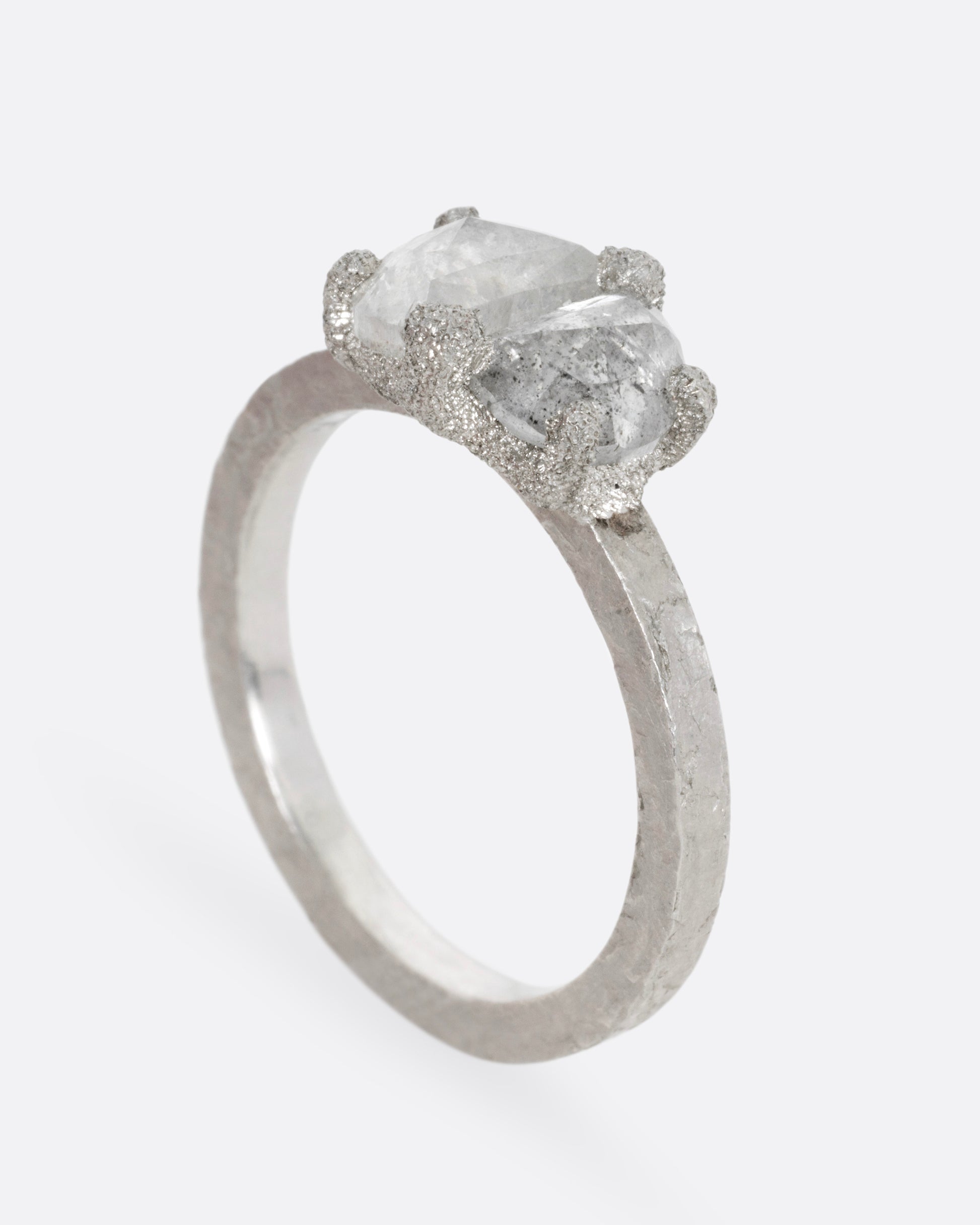A platinum ring with two prong set rose cut diamonds, shown from the side standing up.
