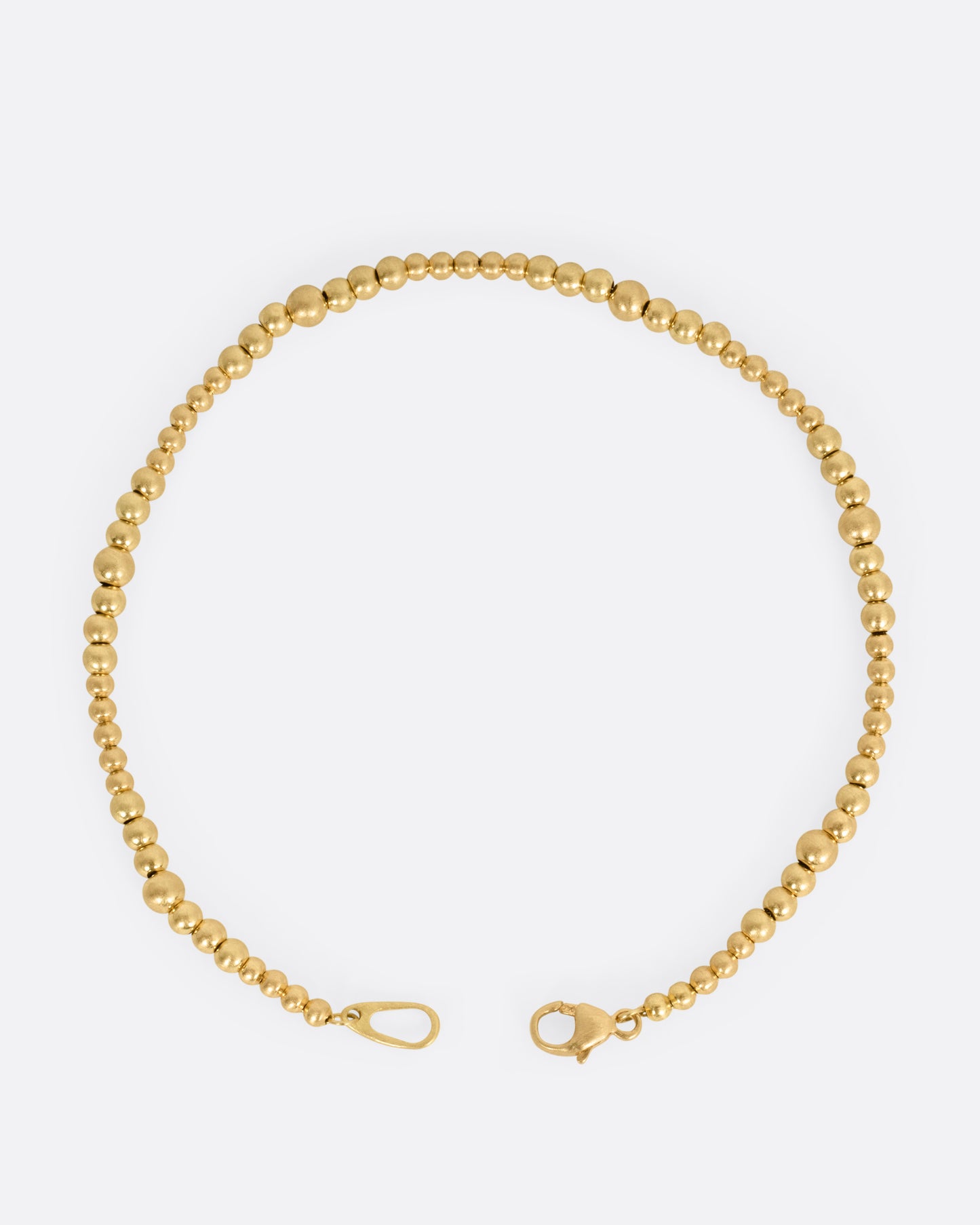 A yellow gold bracelet with graduated beads, shown from the top open.