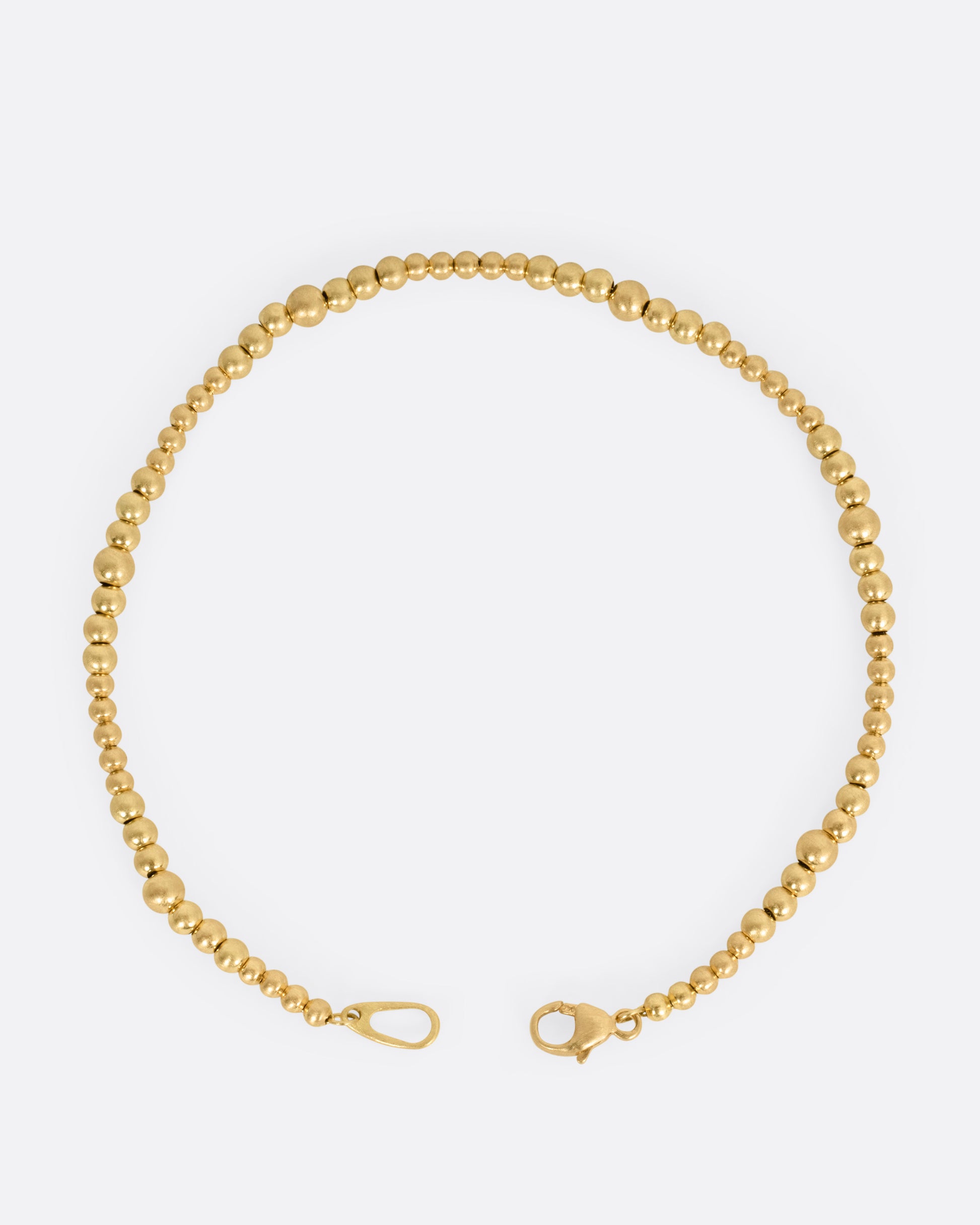 A yellow gold bracelet with graduated beads, shown from the top open.