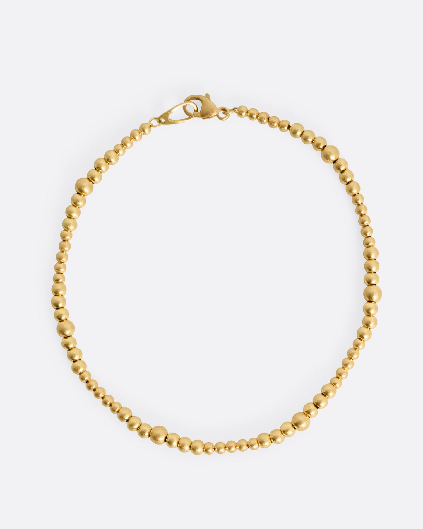 A yellow gold bracelet with graduated beads, shown from the top.