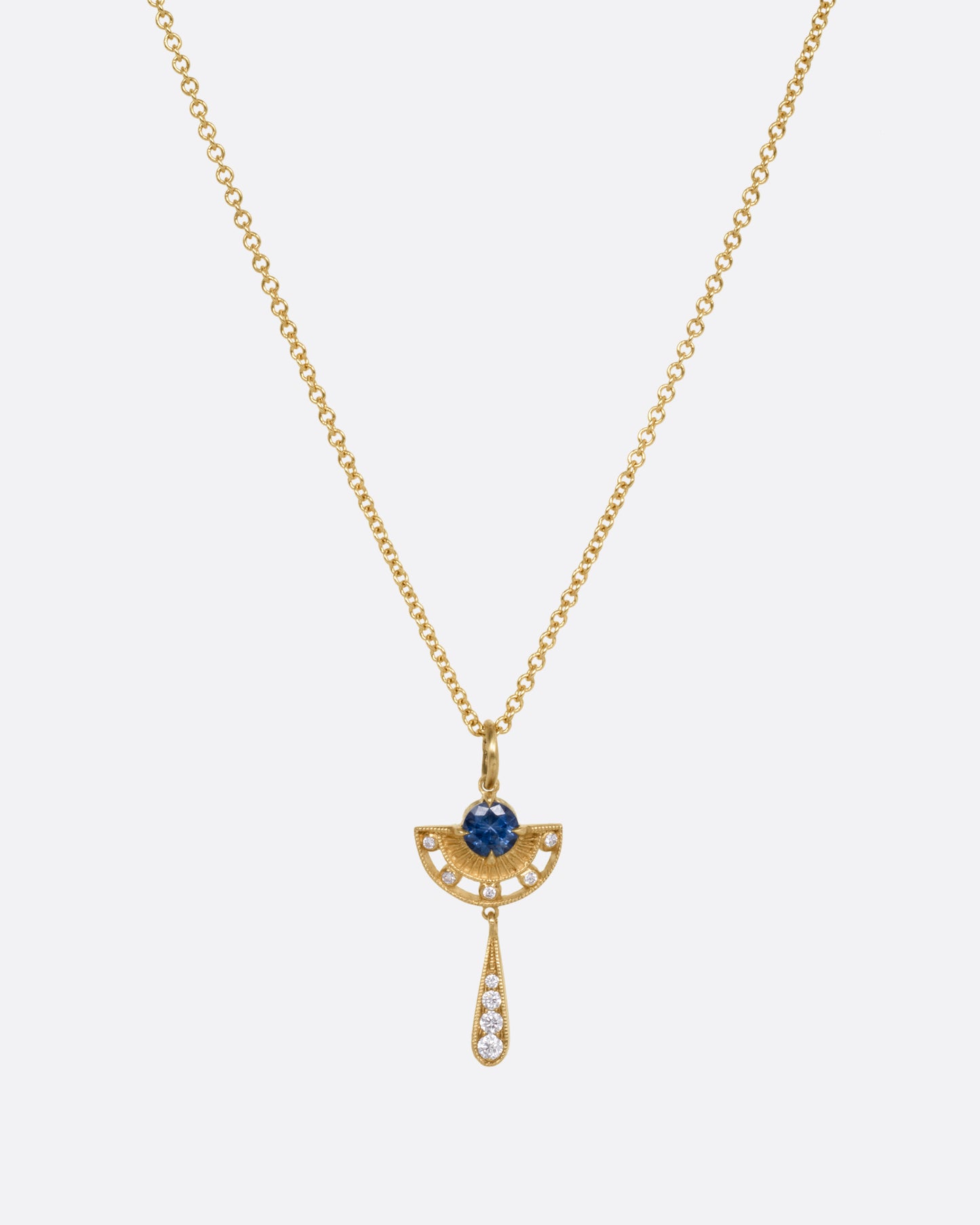 A yellow gold necklace with a sapphire and diamond pendant with open cutouts and a dangle drop. Shown from the front.