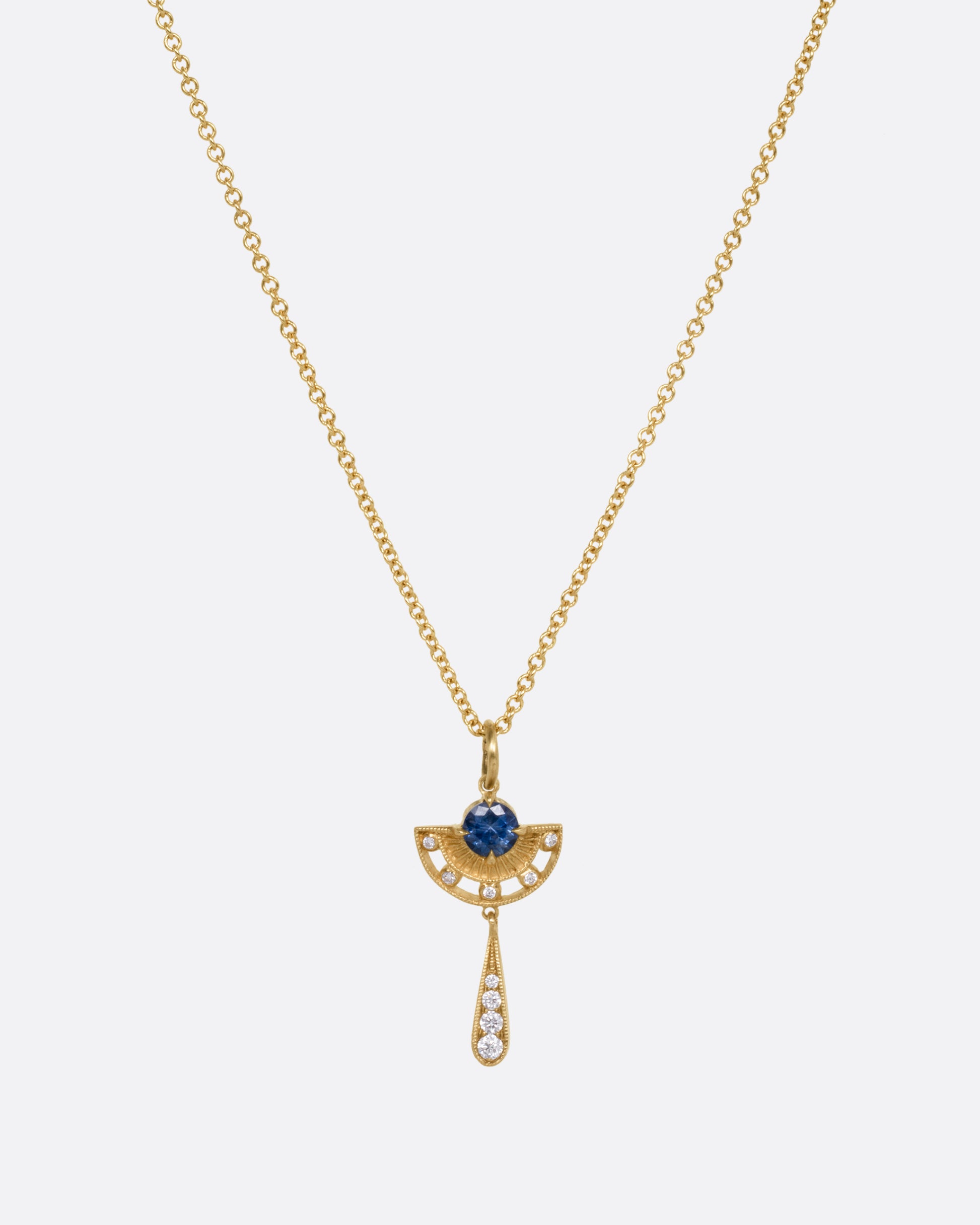 A yellow gold necklace with a sapphire and diamond pendant with open cutouts and a dangle drop. Shown from the front.