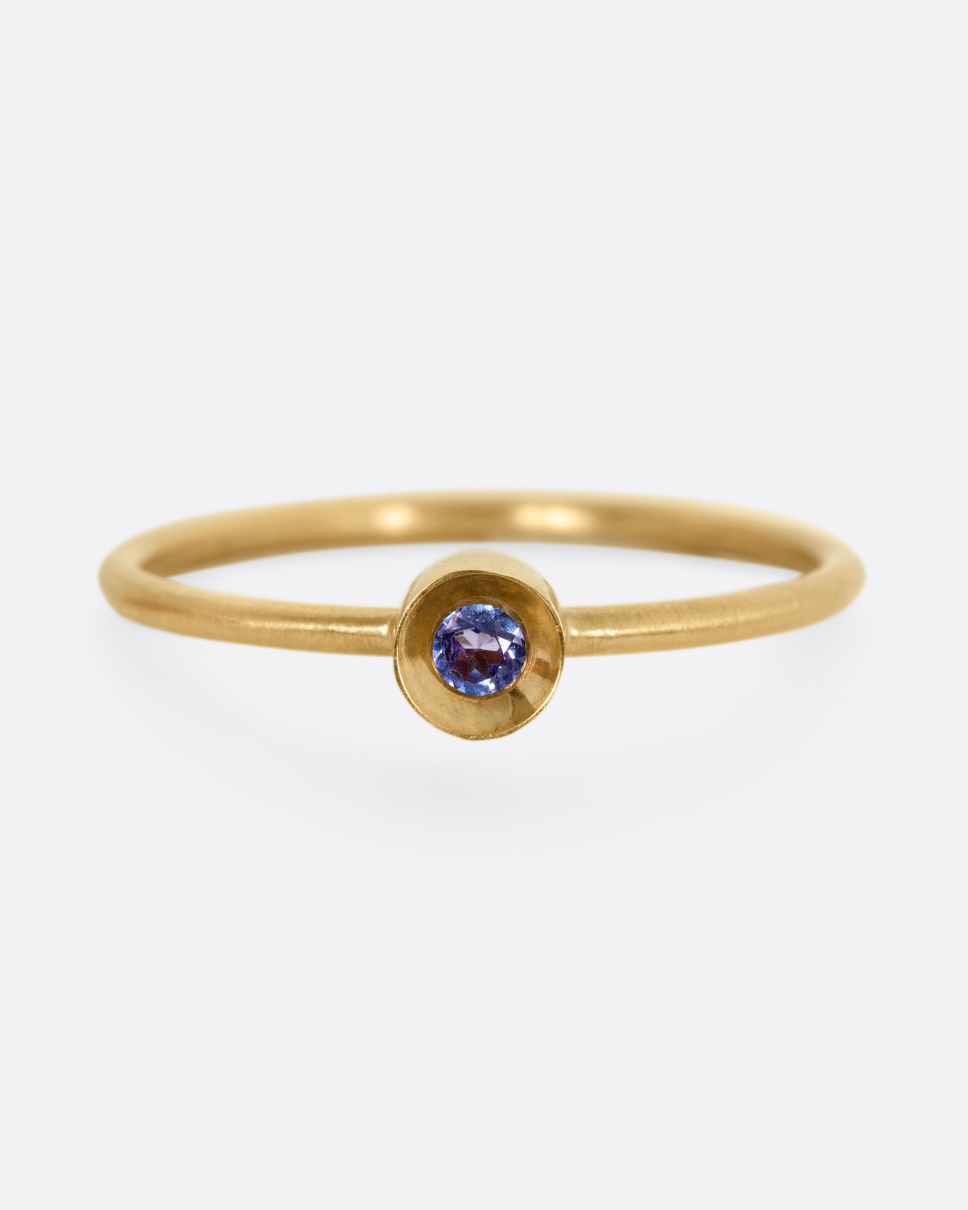 A yellow gold ring with a tanzanite in a raised bezel, shown from the front.