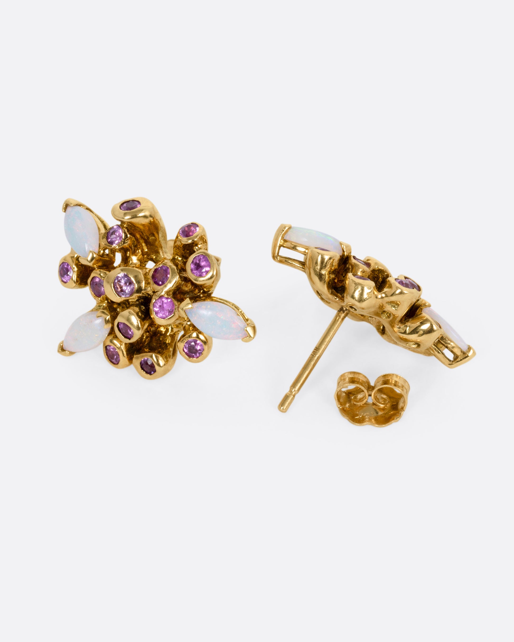 A pair of yellow gold starburst stud earrings with pink sapphires and opals. One is shown from the front, the other from the back open.