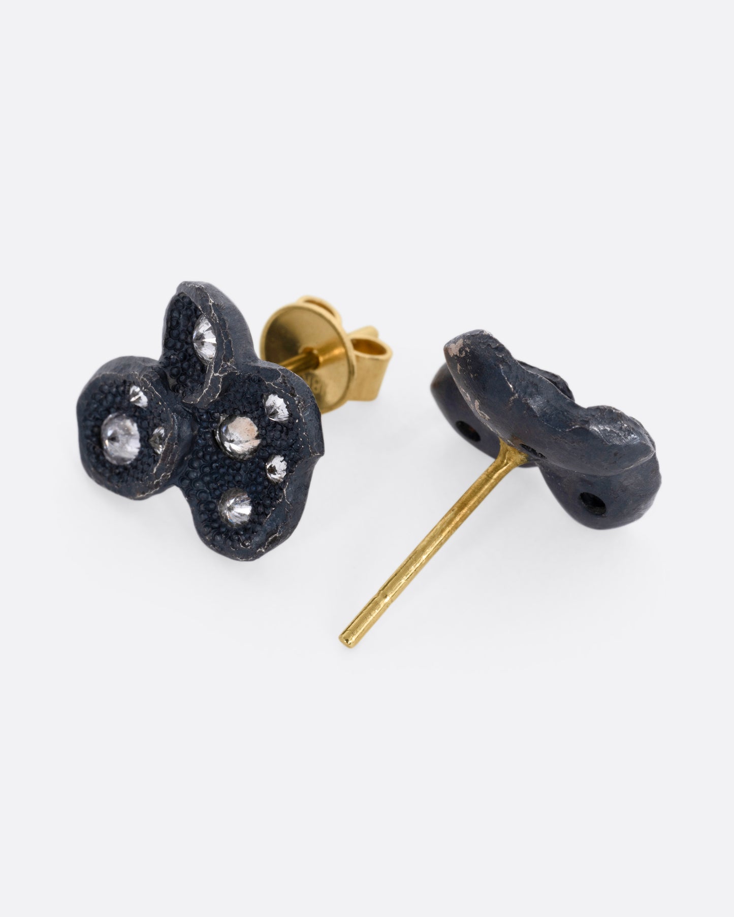 A pair of black oxidized stud earrings with inverted diamonds. One earring is shown from the front, the other from the back, open.