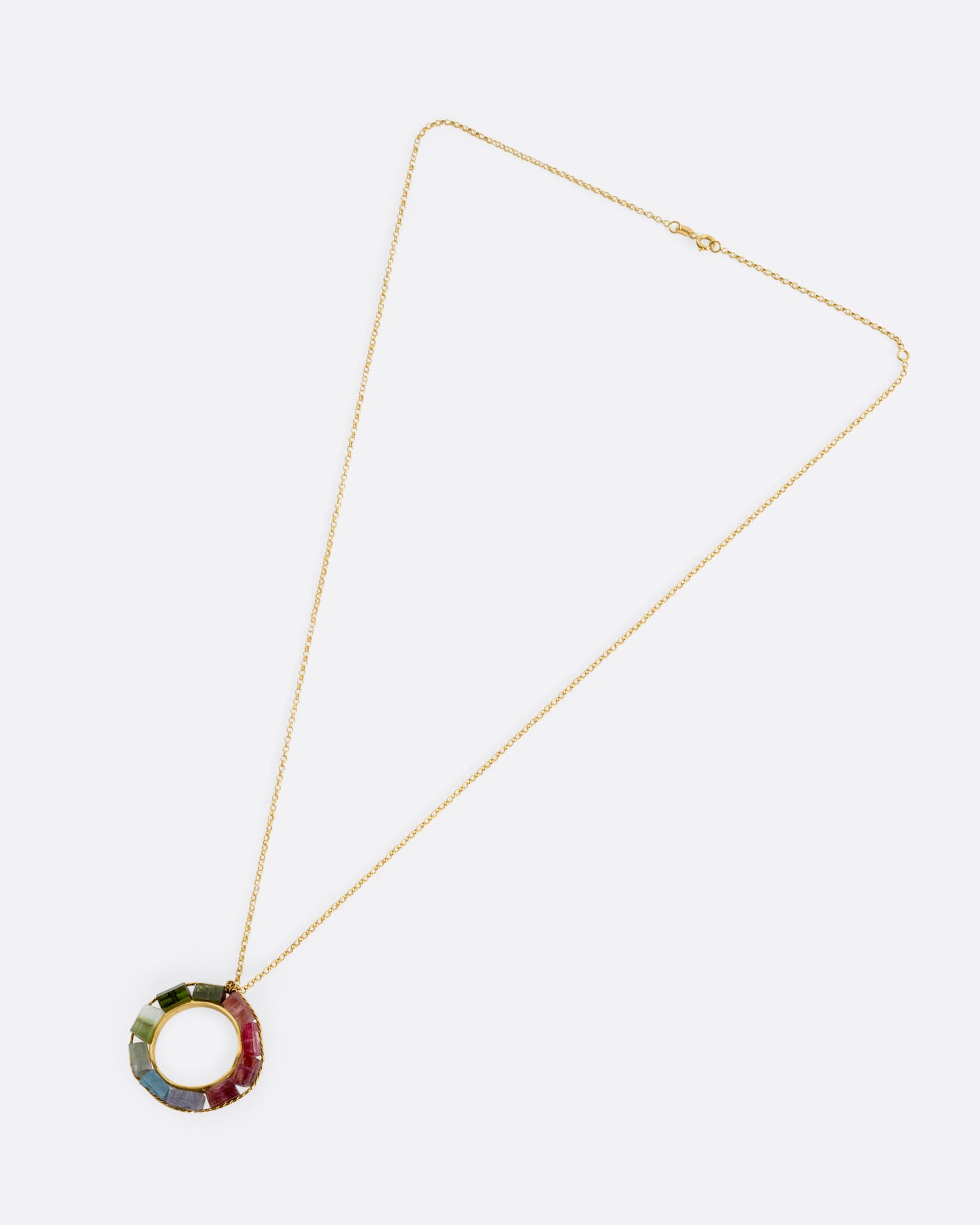 A yellow gold cable chain necklace with an open circular pendant featuring multicolored tourmalines. Shown from the front.