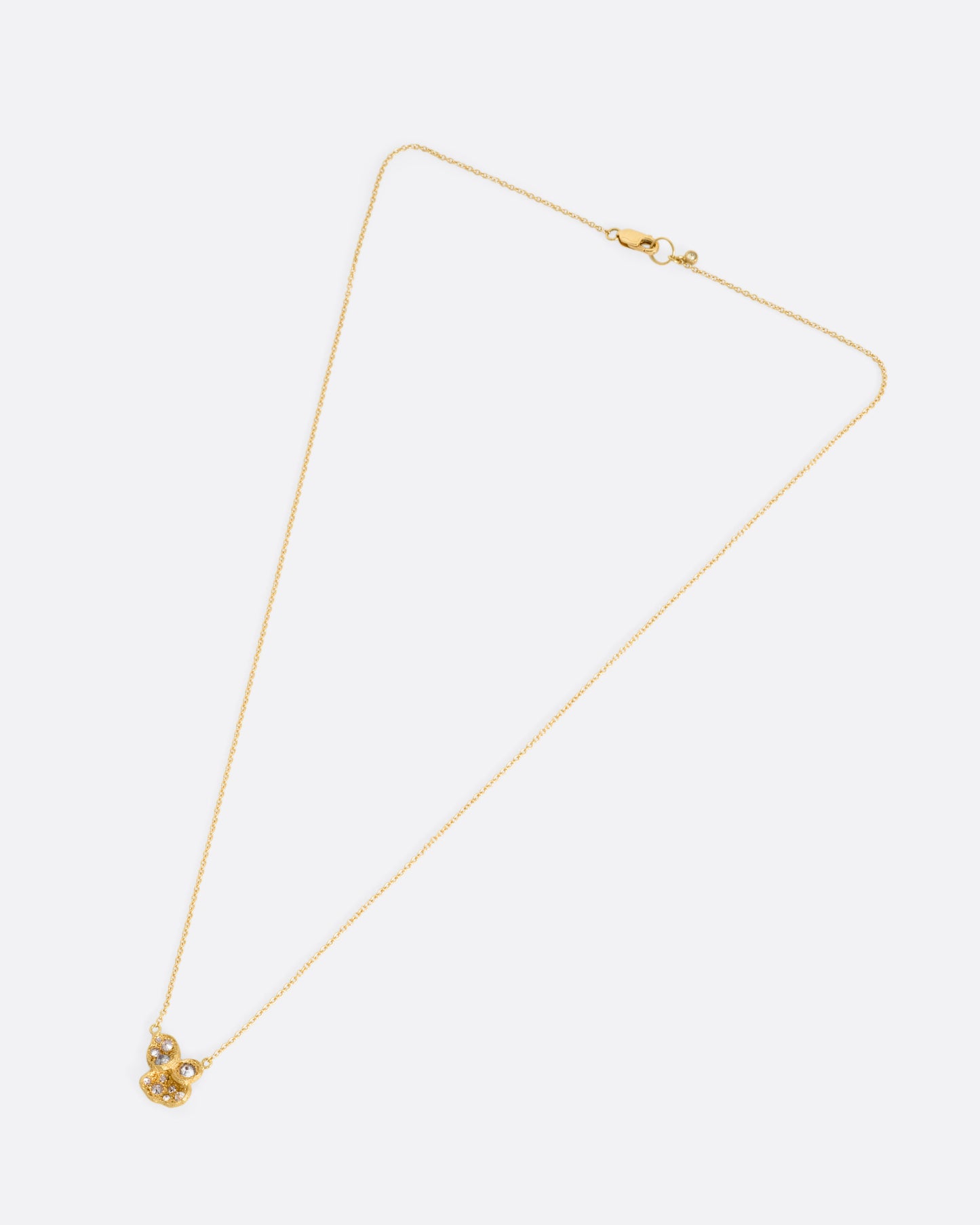 A yellow gold cable chain necklace with a pendant of inverted diamonds in textured divots, shown from the front.