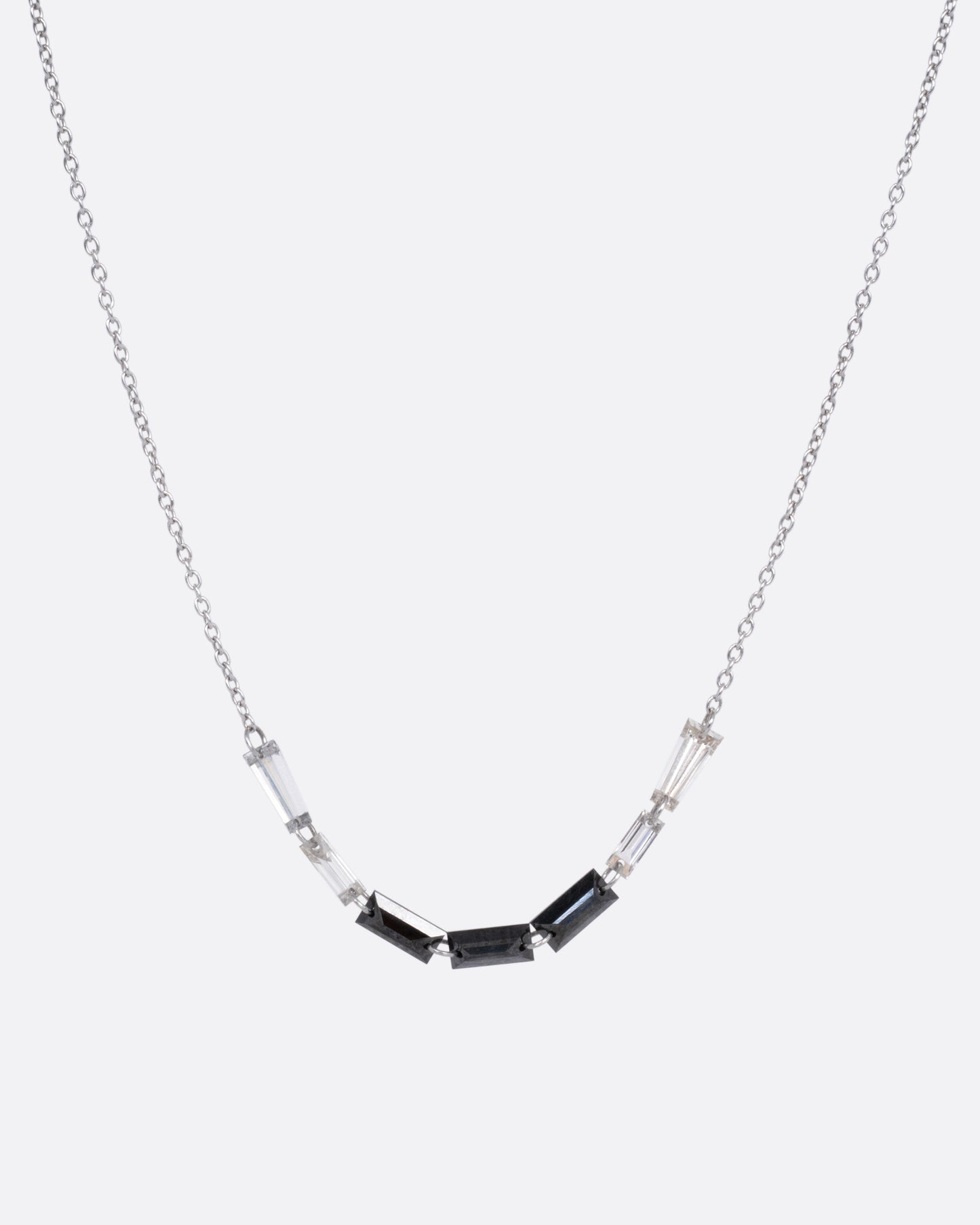 A white gold cable chain with black and white baguette diamonds connected by platinum jump rings, shown from the front.