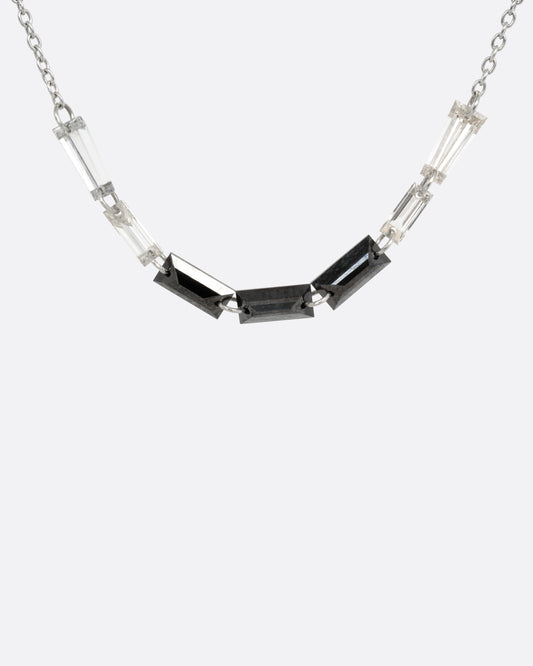 A white gold cable chain with black and white baguette diamonds connected by platinum jump rings, shown from the front.