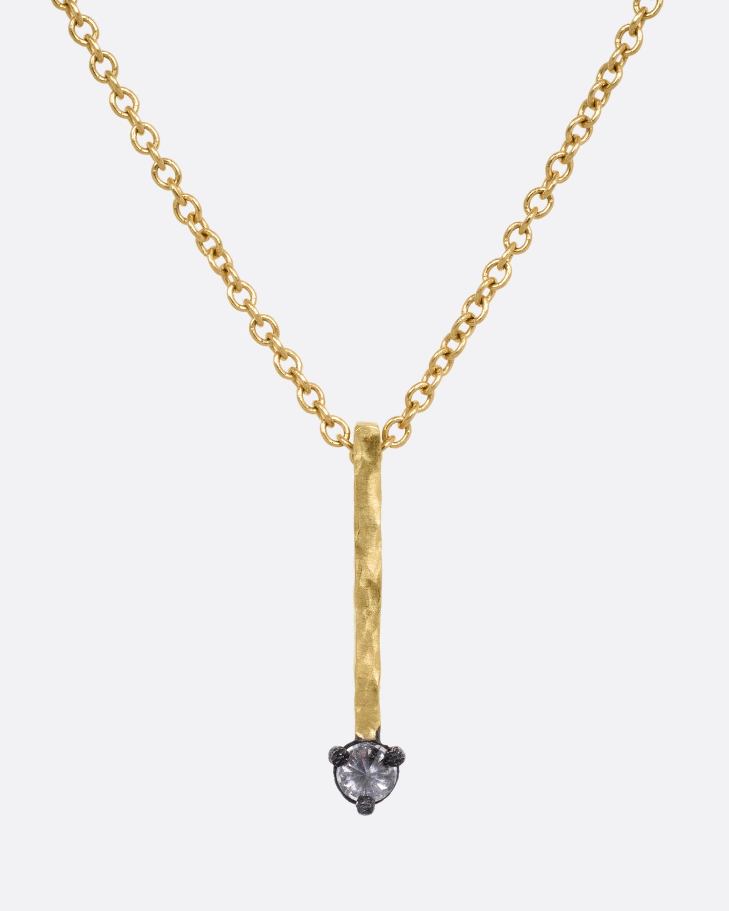 A yellow gold cable chain necklace with a bar pendant studded with an inverted diamond, shown from the front.