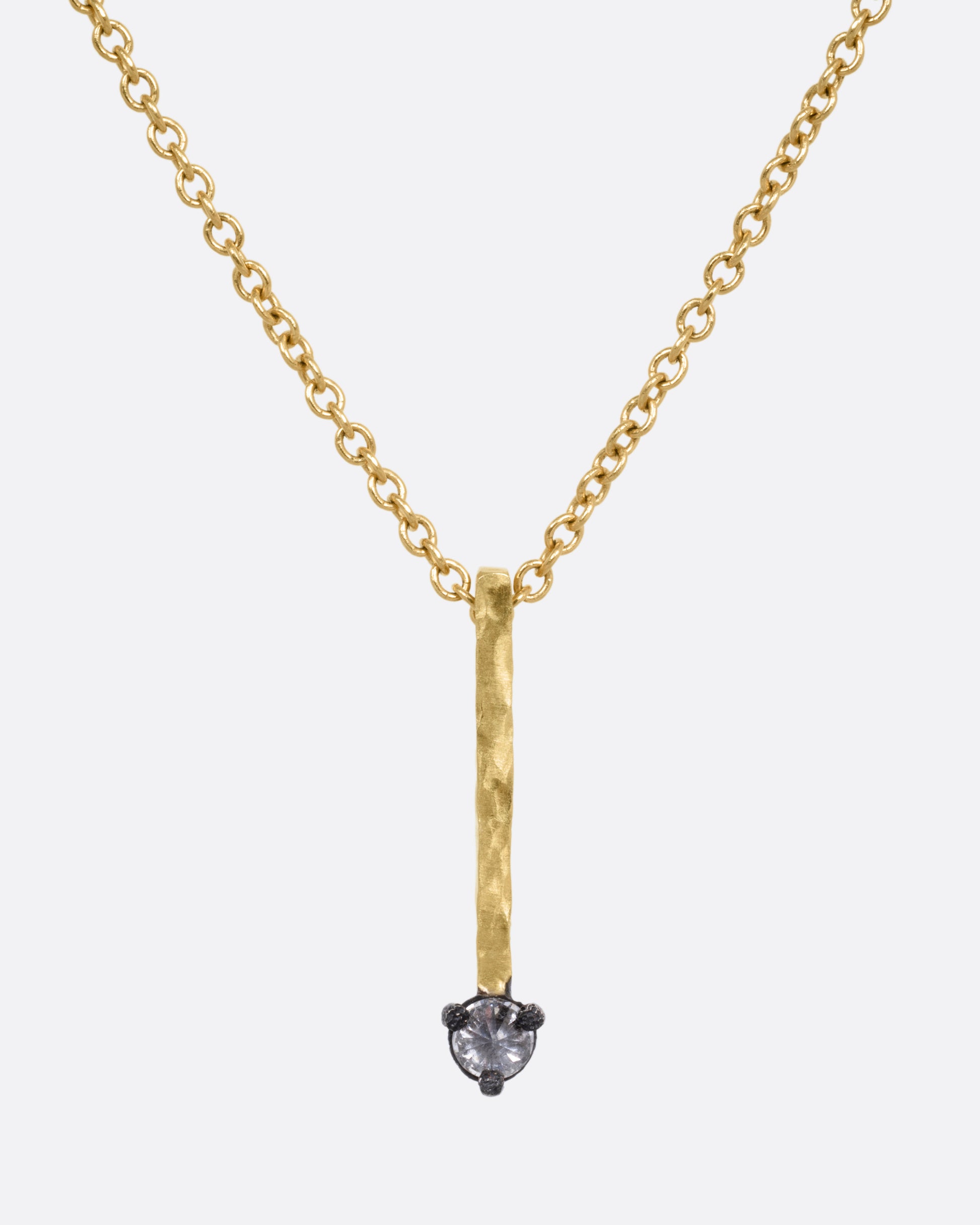 A yellow gold cable chain necklace with a bar pendant studded with an inverted diamond, shown from the front.