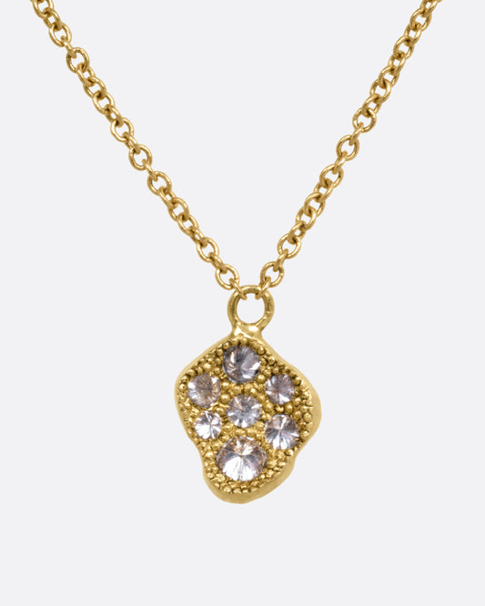 A yellow gold necklace with a concave textured pendant with inverted diamonds. Shown from the front.