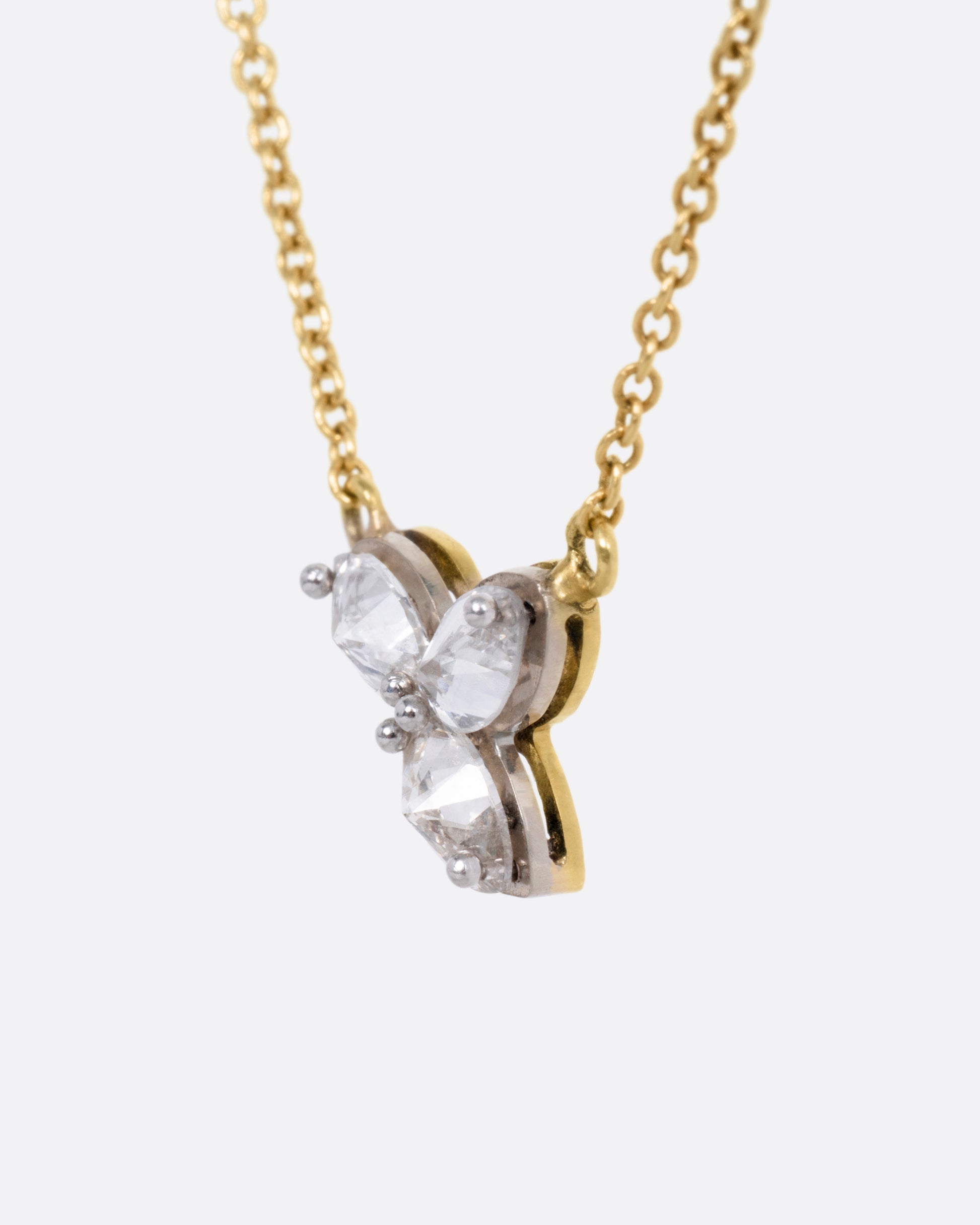 A yellow gold cable chain necklace with a pendant of  three inverted marquise diamonds, shown from the side.