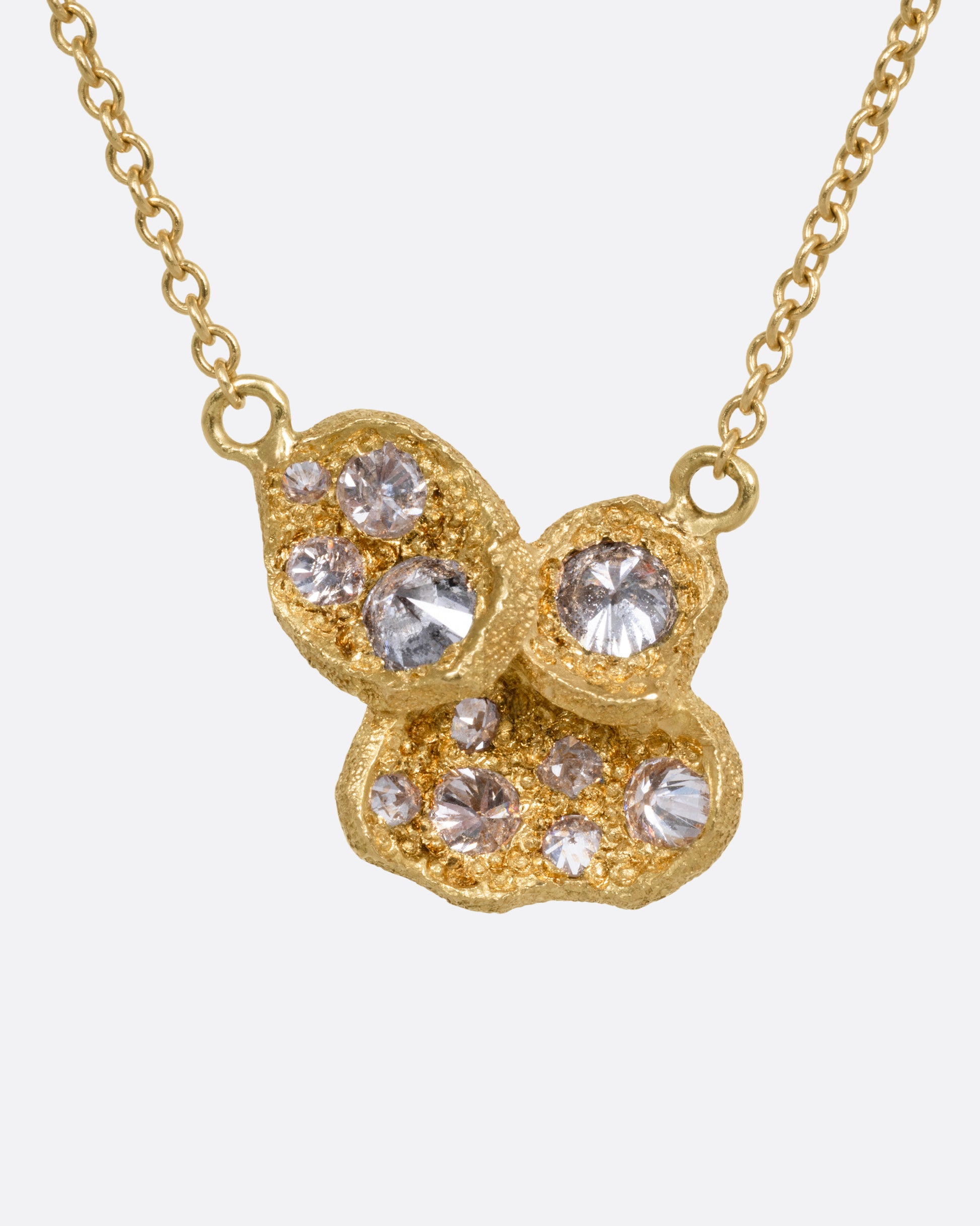A yellow gold cable chain necklace with a pendant of inverted diamonds in textured divots, shown from the front.