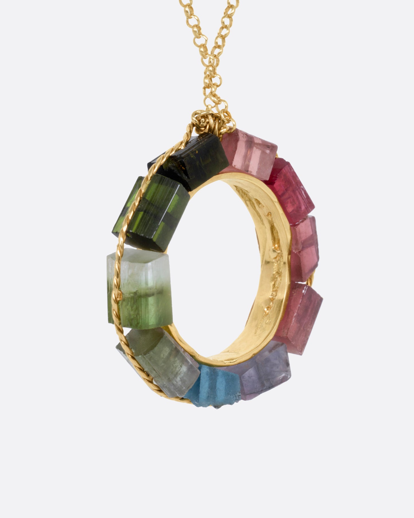 A yellow gold cable chain necklace with an open circular pendant featuring multicolored tourmalines. Shown from the side.