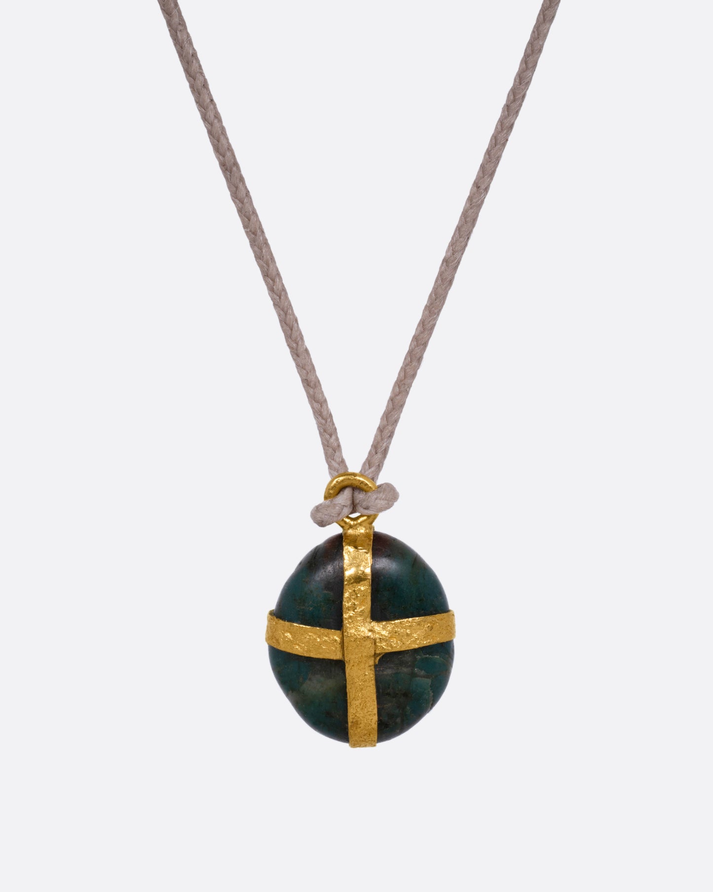 A Japanese river pebble pendant wrapped in yellow gold and hanging from a cord, shown from the front.