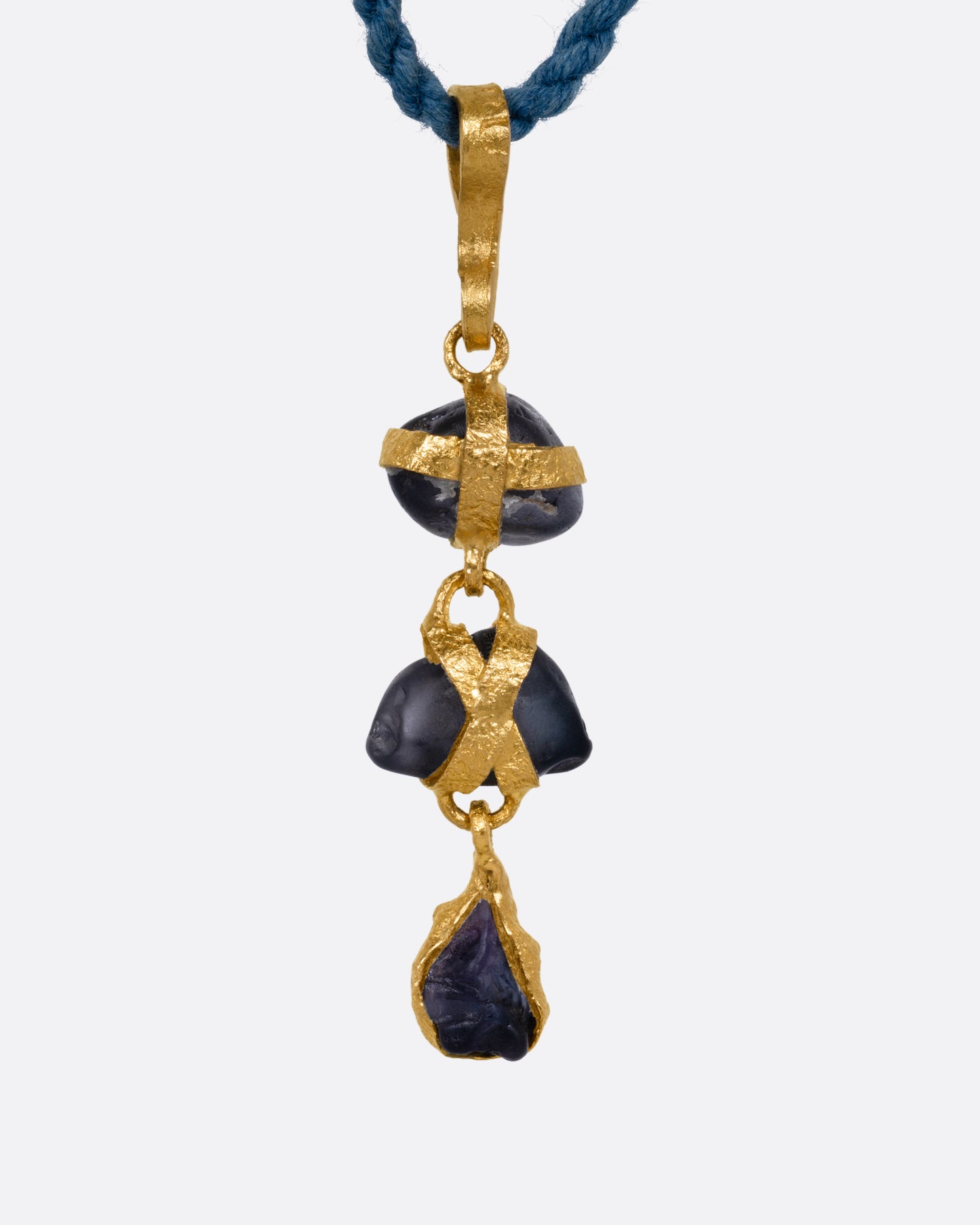 A yellow gold pendant with three  raw sapphires on a cord, shown from the front.
