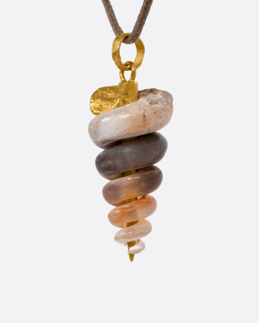 A yellow gold pendant with a  fossilized snail on a cord, shown from the side.