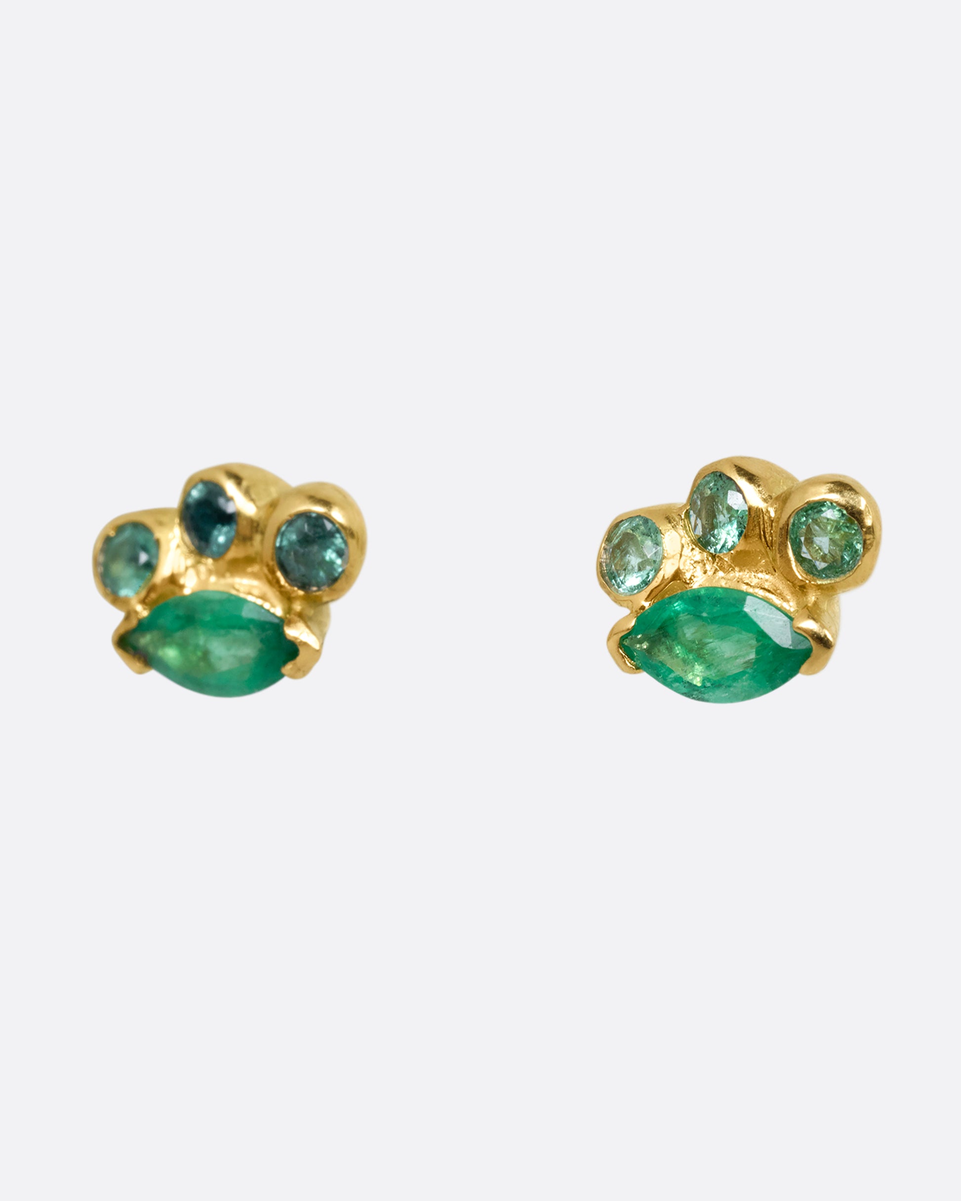 A pair of yellow gold stud earrings with round and marquise emeralds. Shown from the side. 