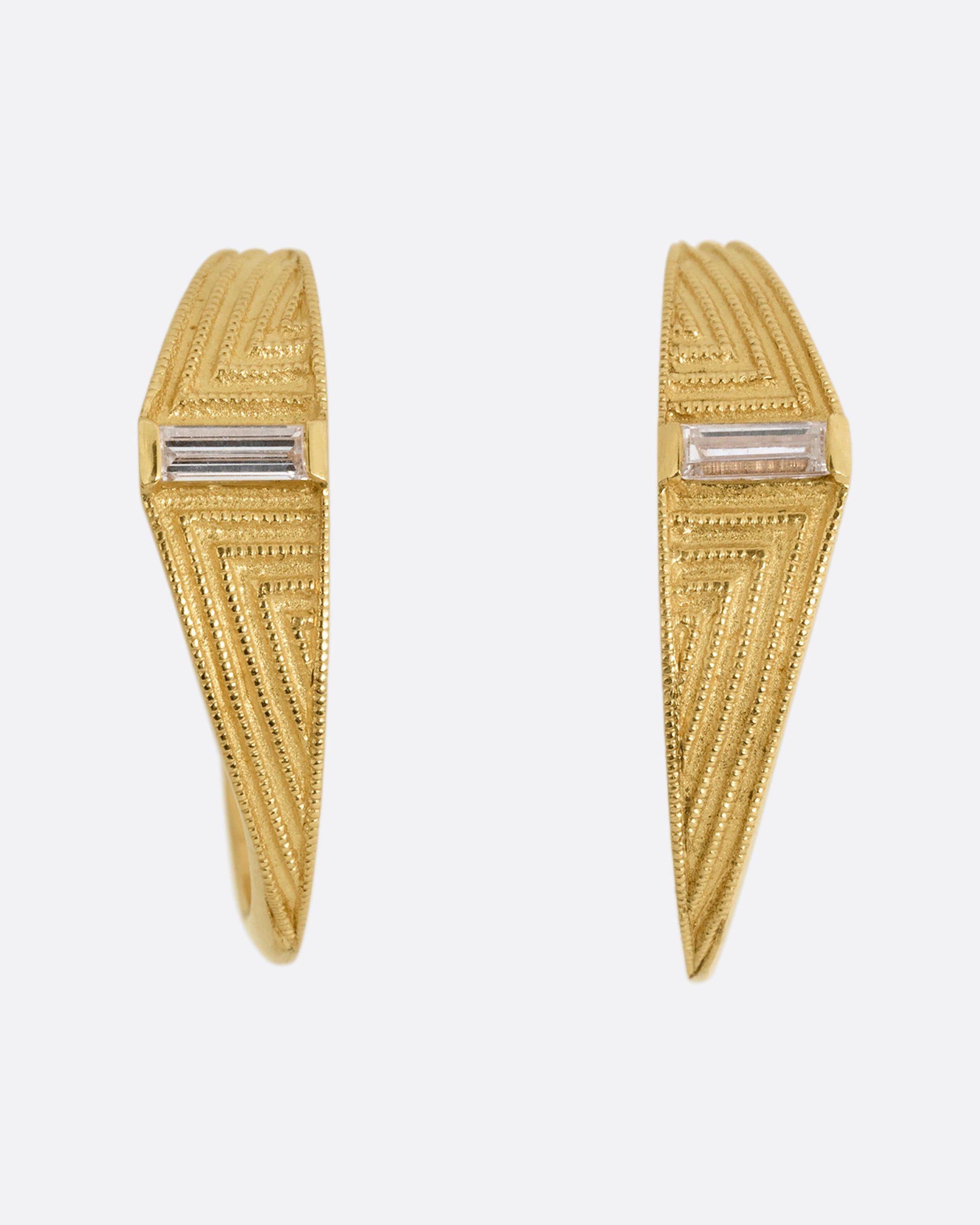 A pair of yellow gold deco inspired hoops with a baguette diamond and a geometric pattern. Shown from the front.