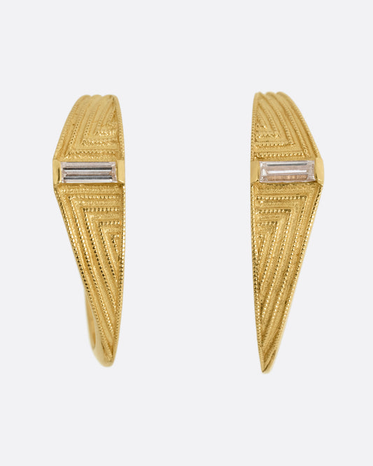 A pair of yellow gold deco inspired hoops with a baguette diamond and a geometric pattern. Shown from the front.