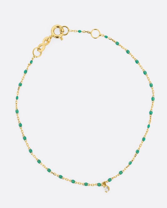 A yellow gold cable chain bracelet with green resin droplets throughout and a single diamond charm. Shown from the front.