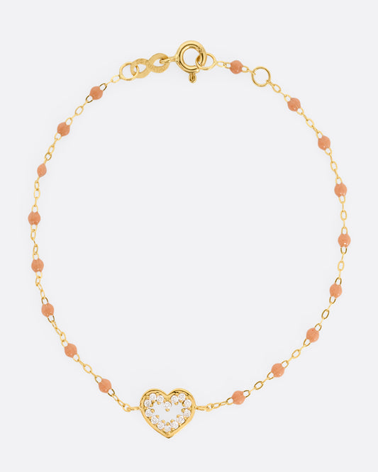 A yellow gold cable chain bracelet with a diamond lined heart charm and caramel brown resin droplets throughout. Shown from the front.