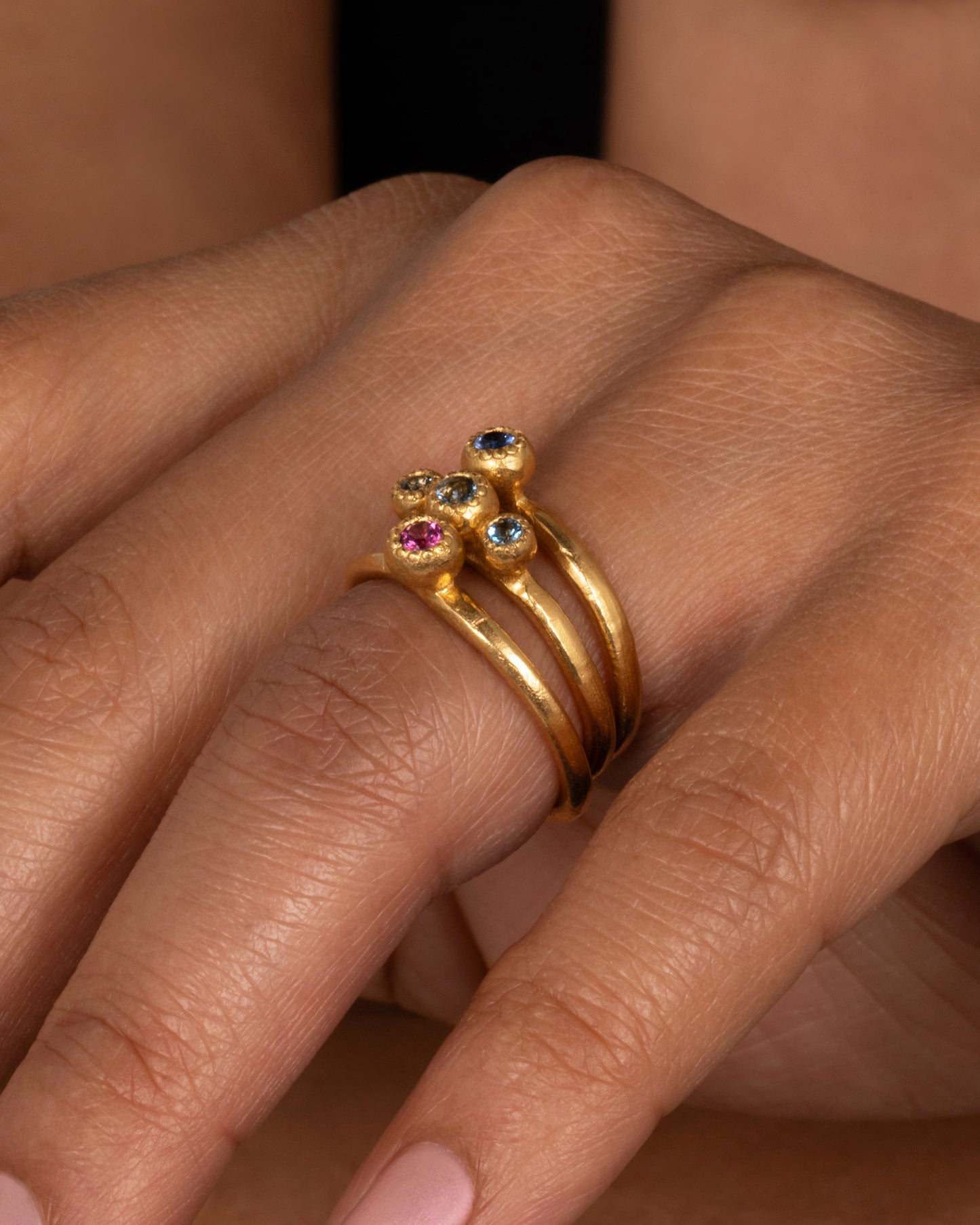 A deep blue sapphire solitaire ring; perfect on its own or stacked with its emerald counterpart. Shown on a finger.