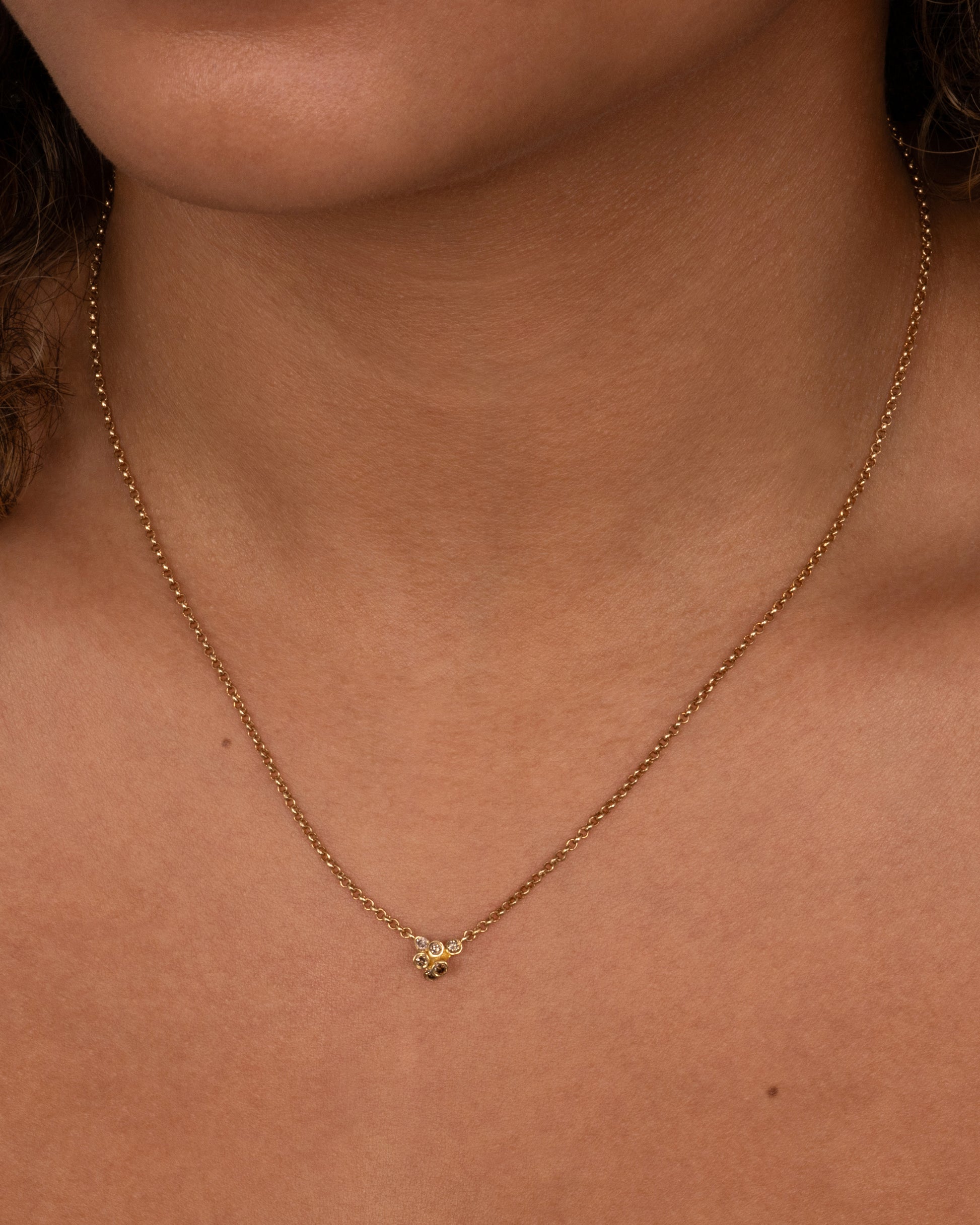 A yellow gold cable chain necklace with a central cluster of dimensional cognac diamonds. Shown from the front on a person.
