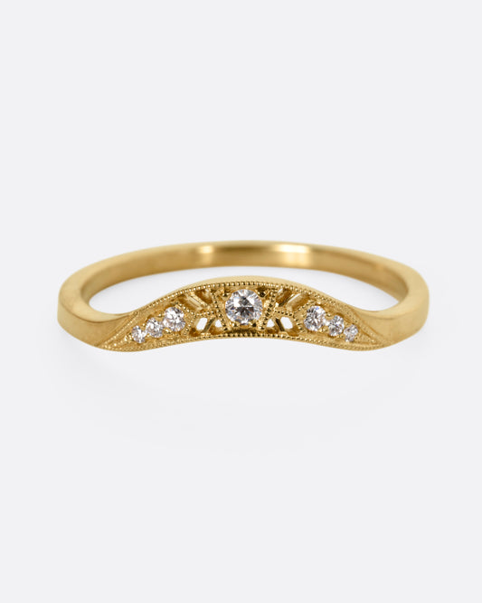 A yellow gold ring with diamonds and small cutouts, shown from the front.