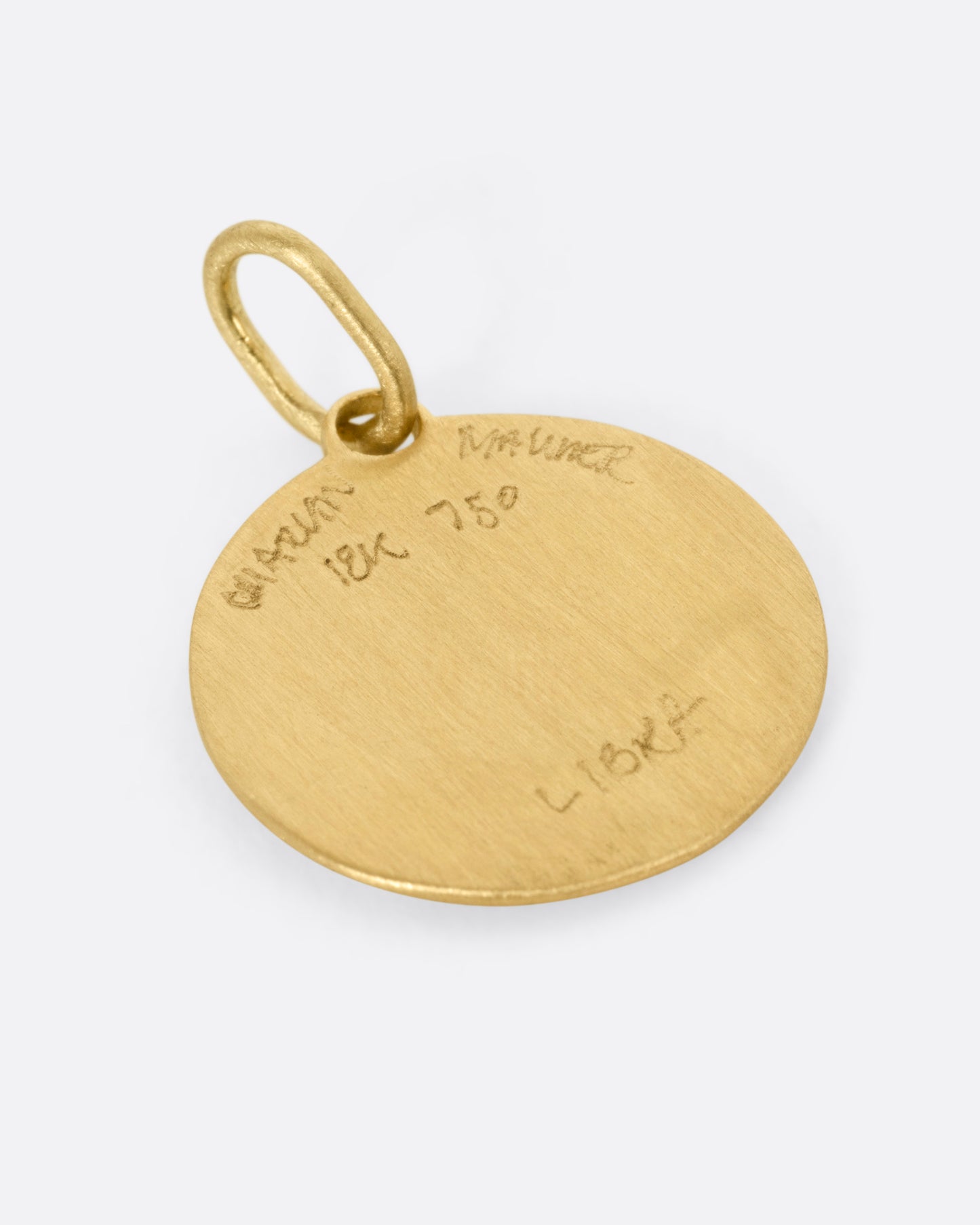 A circular yellow gold Libra pendant with the scales of balance, shown from the back.