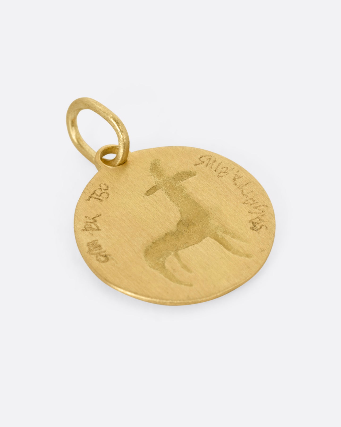 A yellow gold circular Sagittarius pendant with the archer, shown from the back.