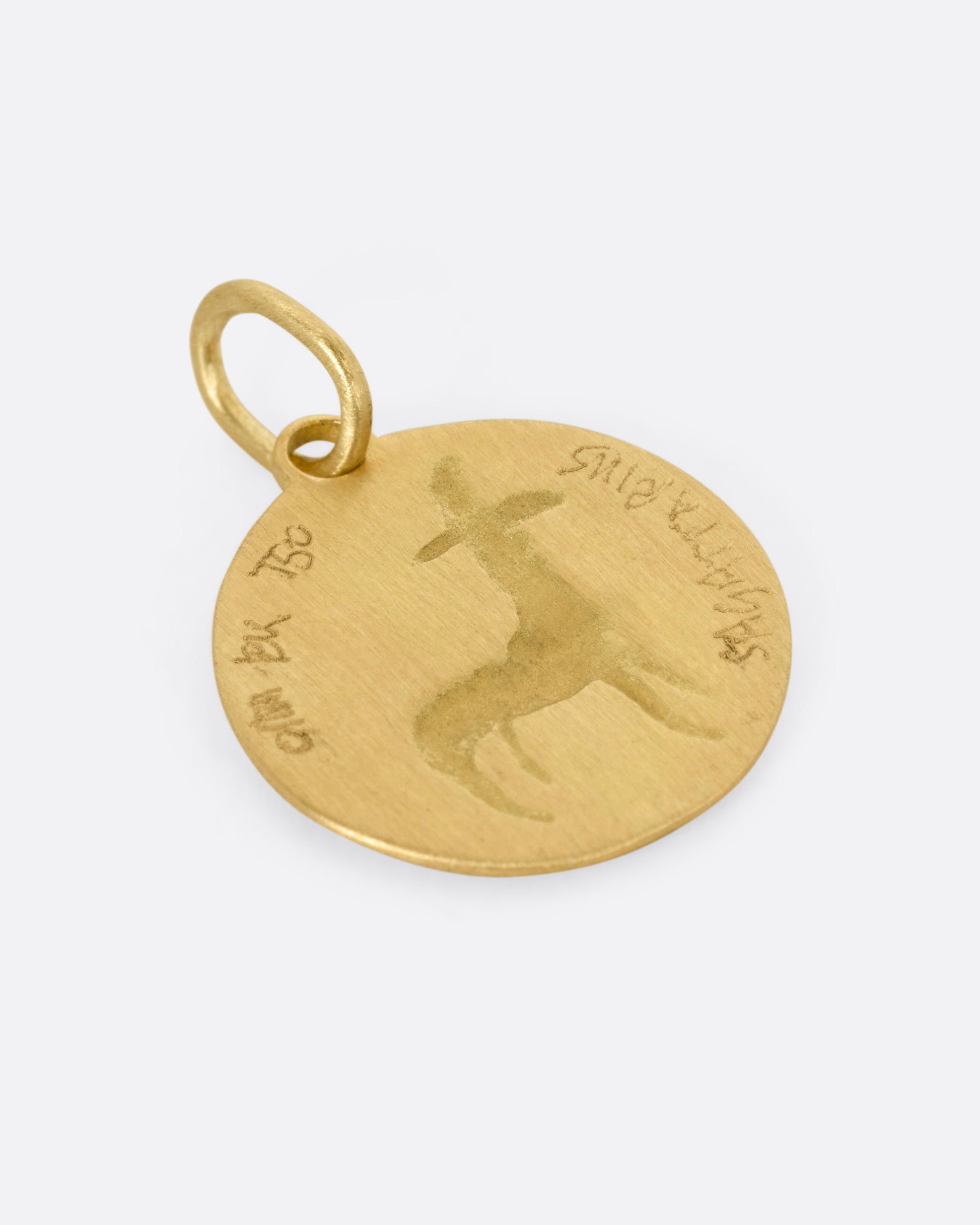 A yellow gold circular Sagittarius pendant with the archer, shown from the back.