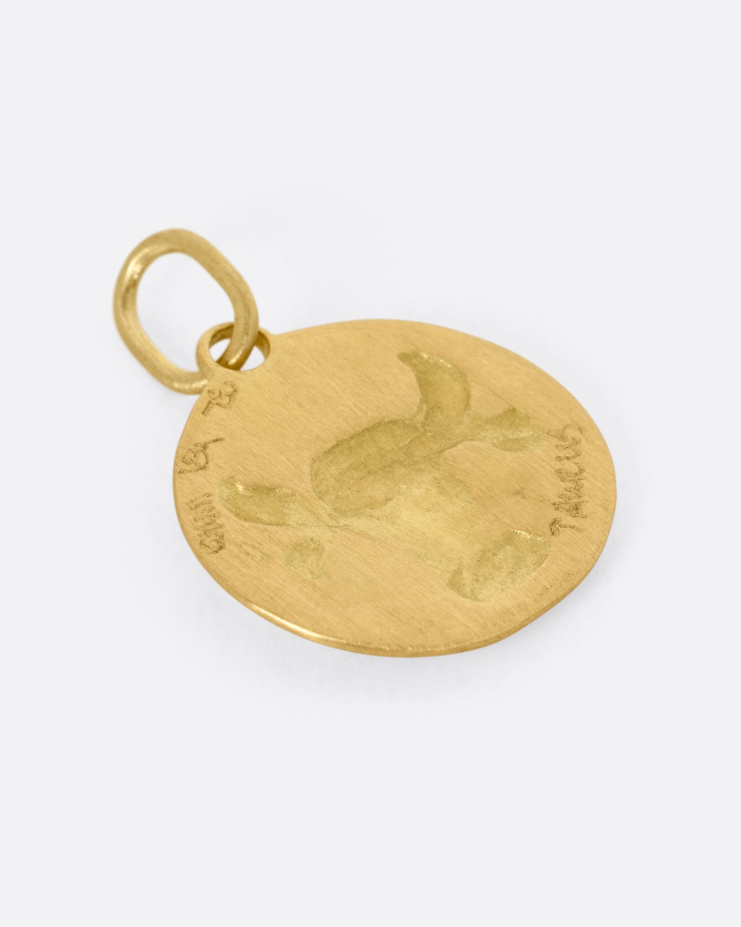 A circular yellow gold Taurus pendant with a bull head, shown from the back.