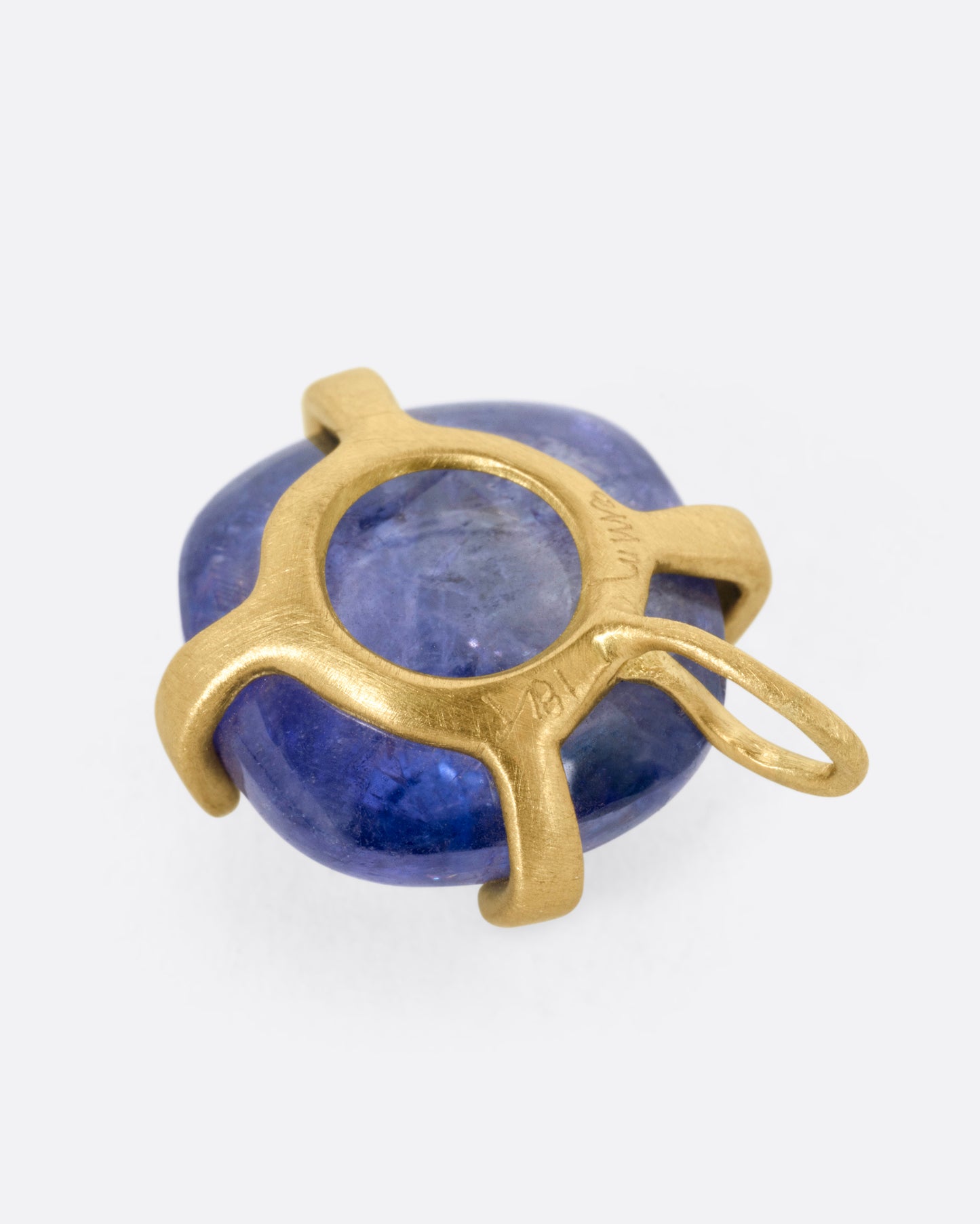 A yellow gold charm with a prong set tanzanite cabochon, shown from the back.