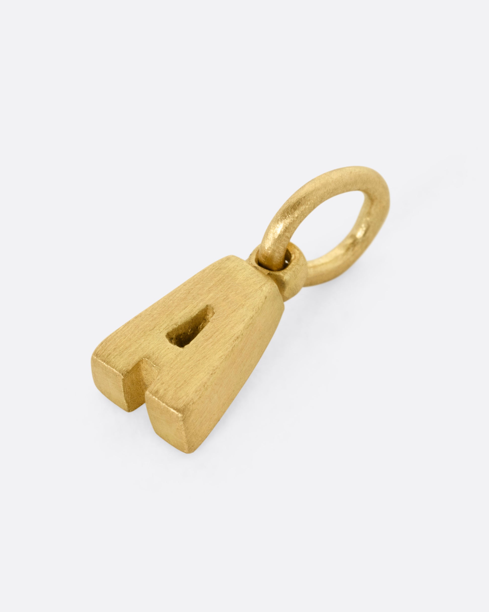 A yellow gold letter 'A' pendant shown from the side.