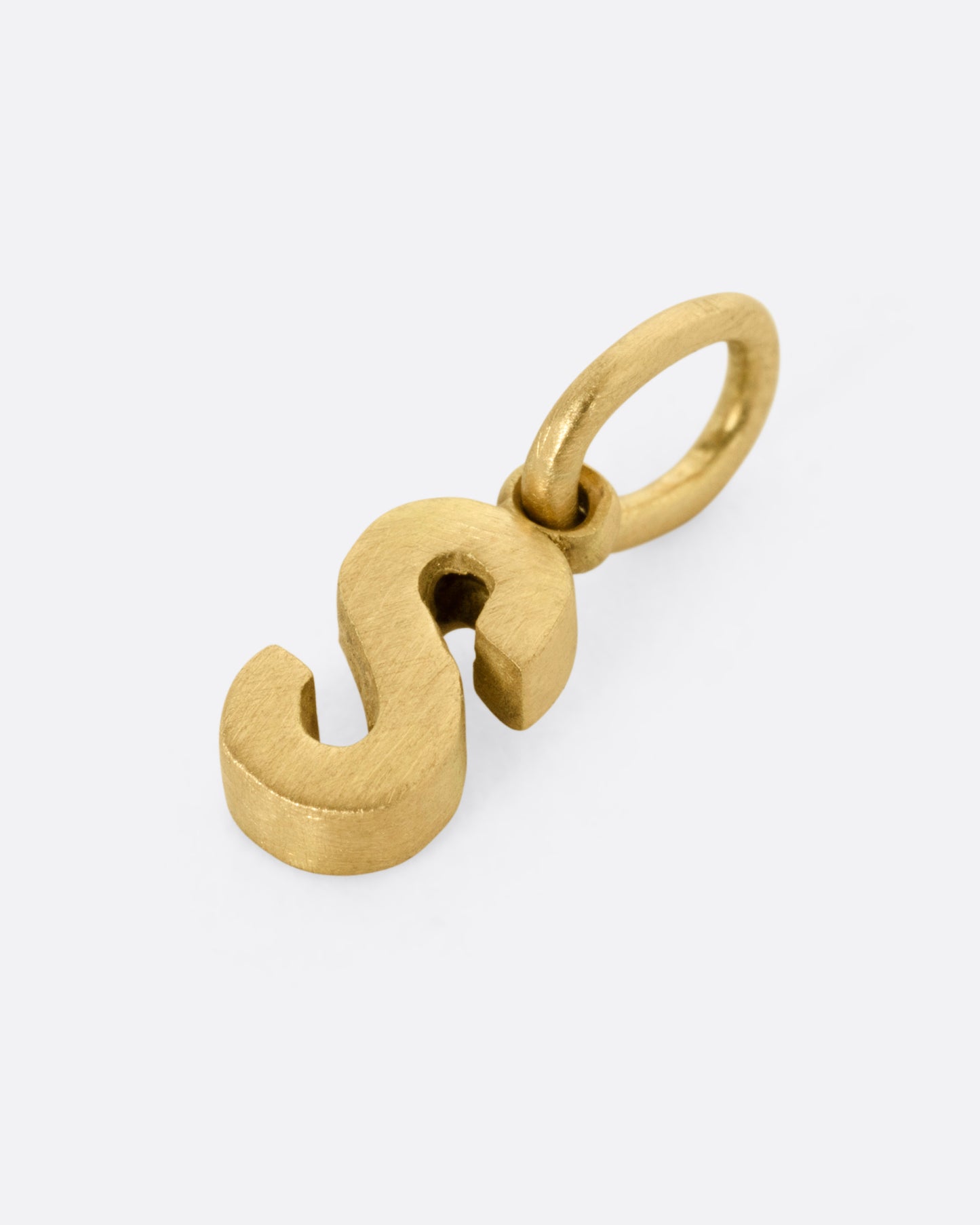 A yellow gold letter 'S' pendant shown from the side.