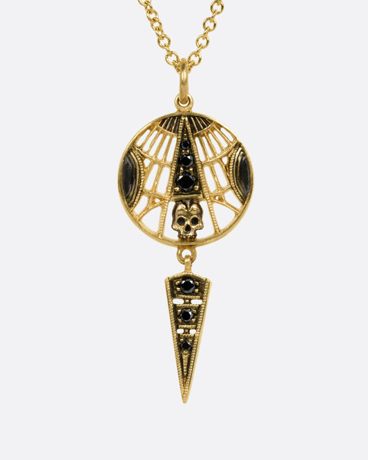 A yellow gold necklace with a circular pendant, triangular dangle, a skull, black diamonds, and cutouts. Shown from the front.