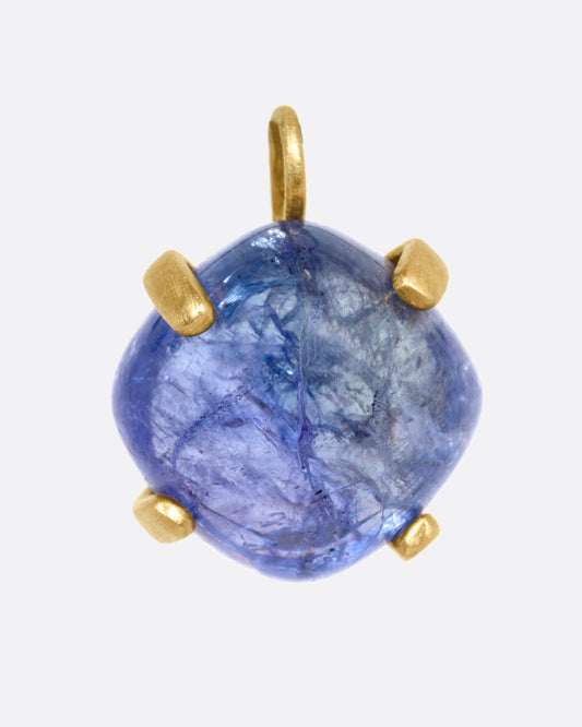 A yellow gold charm with a prong set tanzanite cabochon, shown from the front.