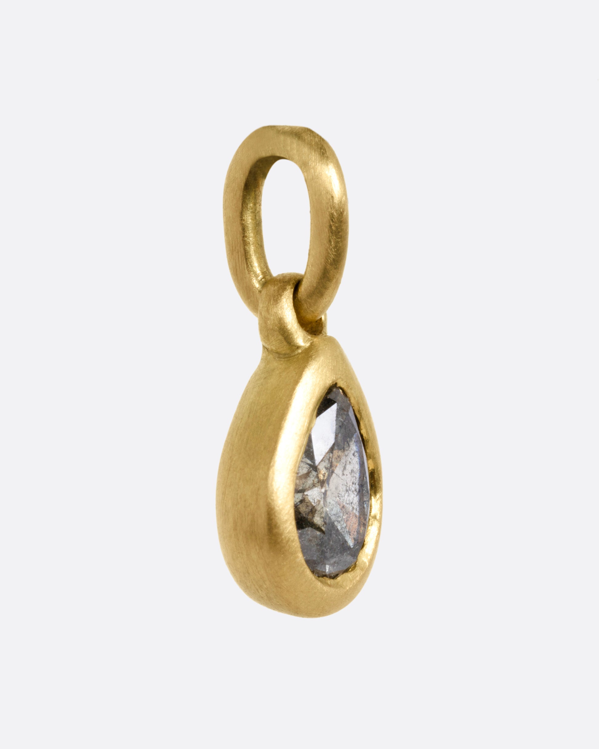 A yellow gold pendant with a pear shaped grey diamond, shown from the side.