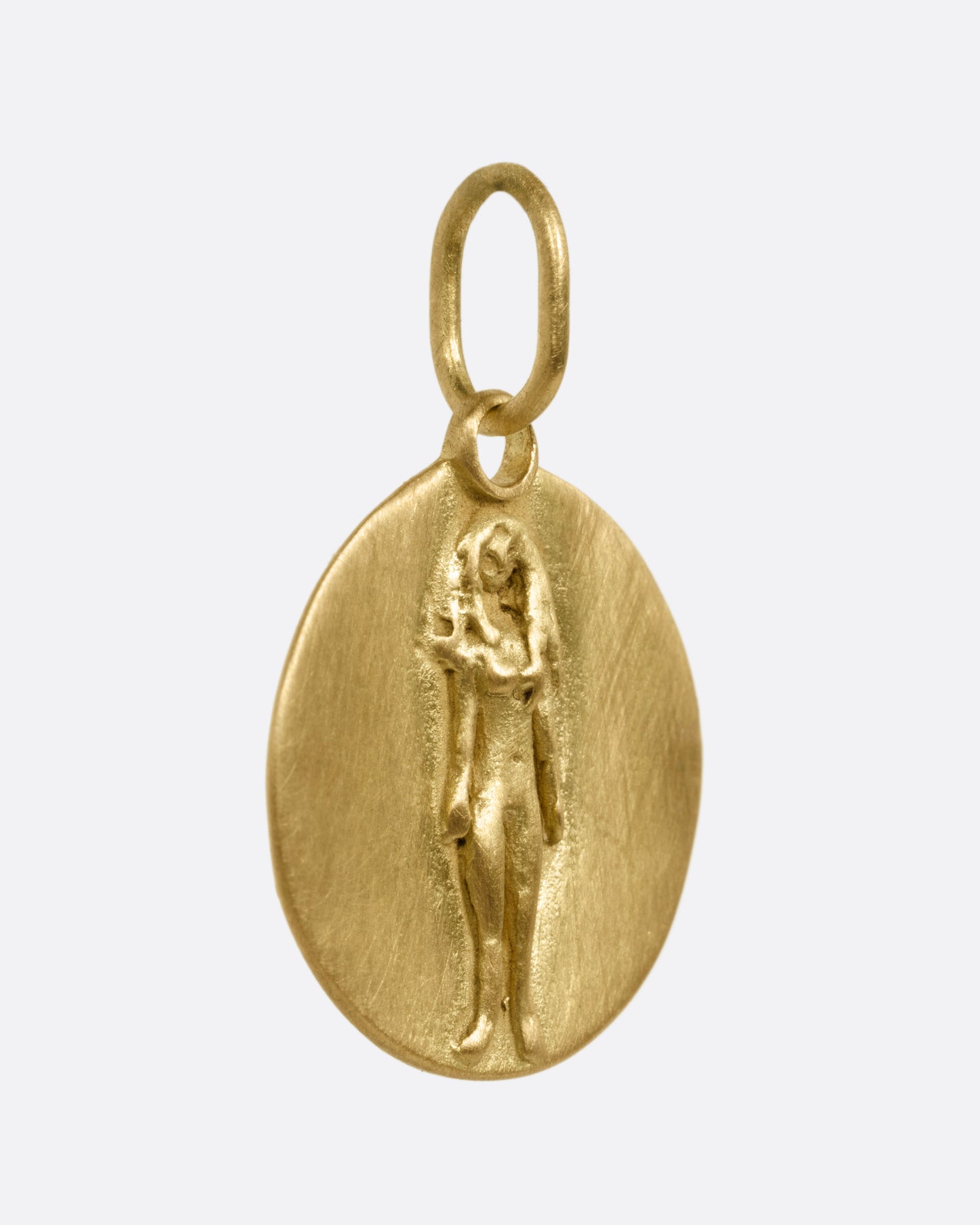 A circular yellow gold Virgo pendant with a female figure, shown from the side.