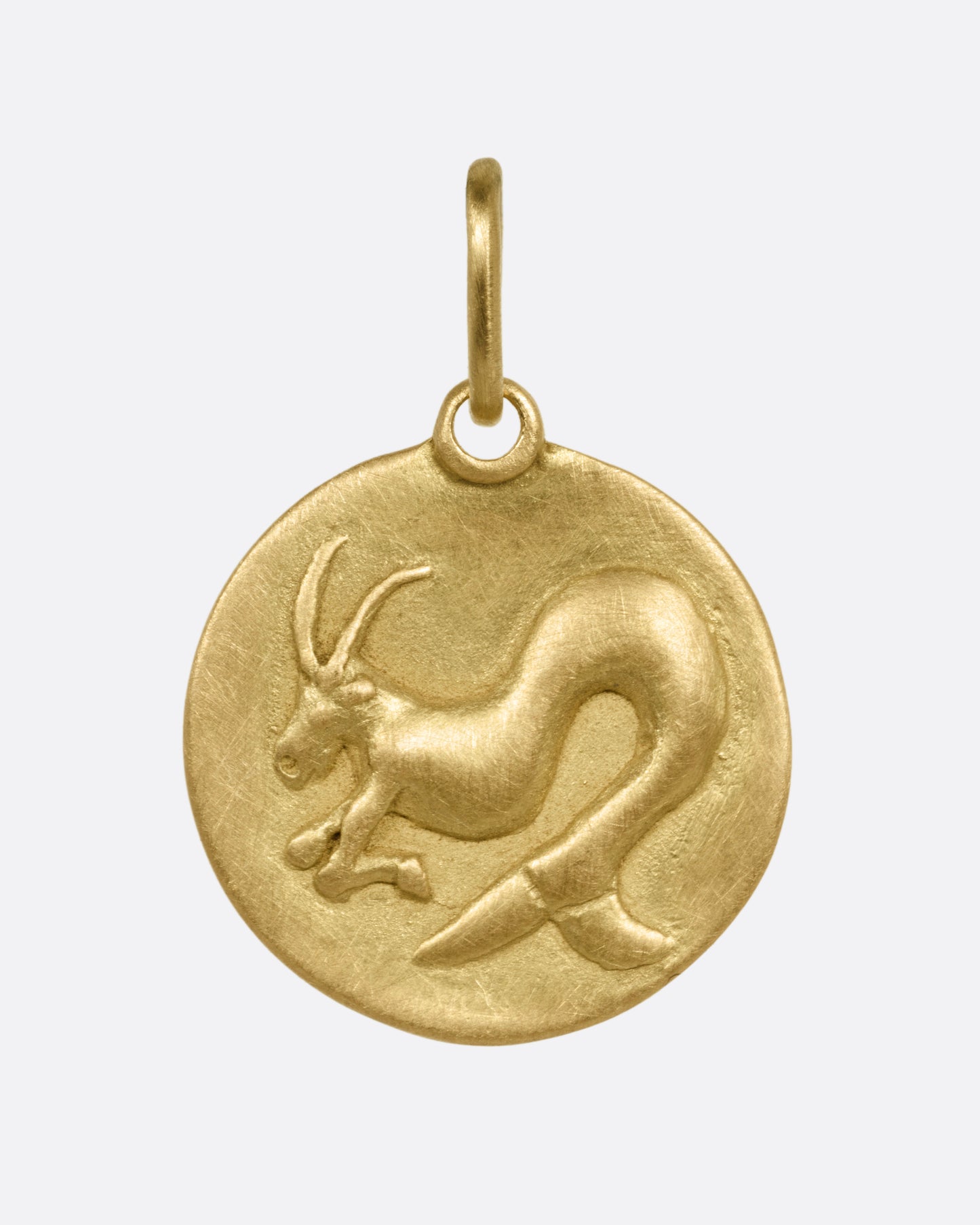 A circular yellow gold Capricorn pendant with a sea goat, shown from the front.
